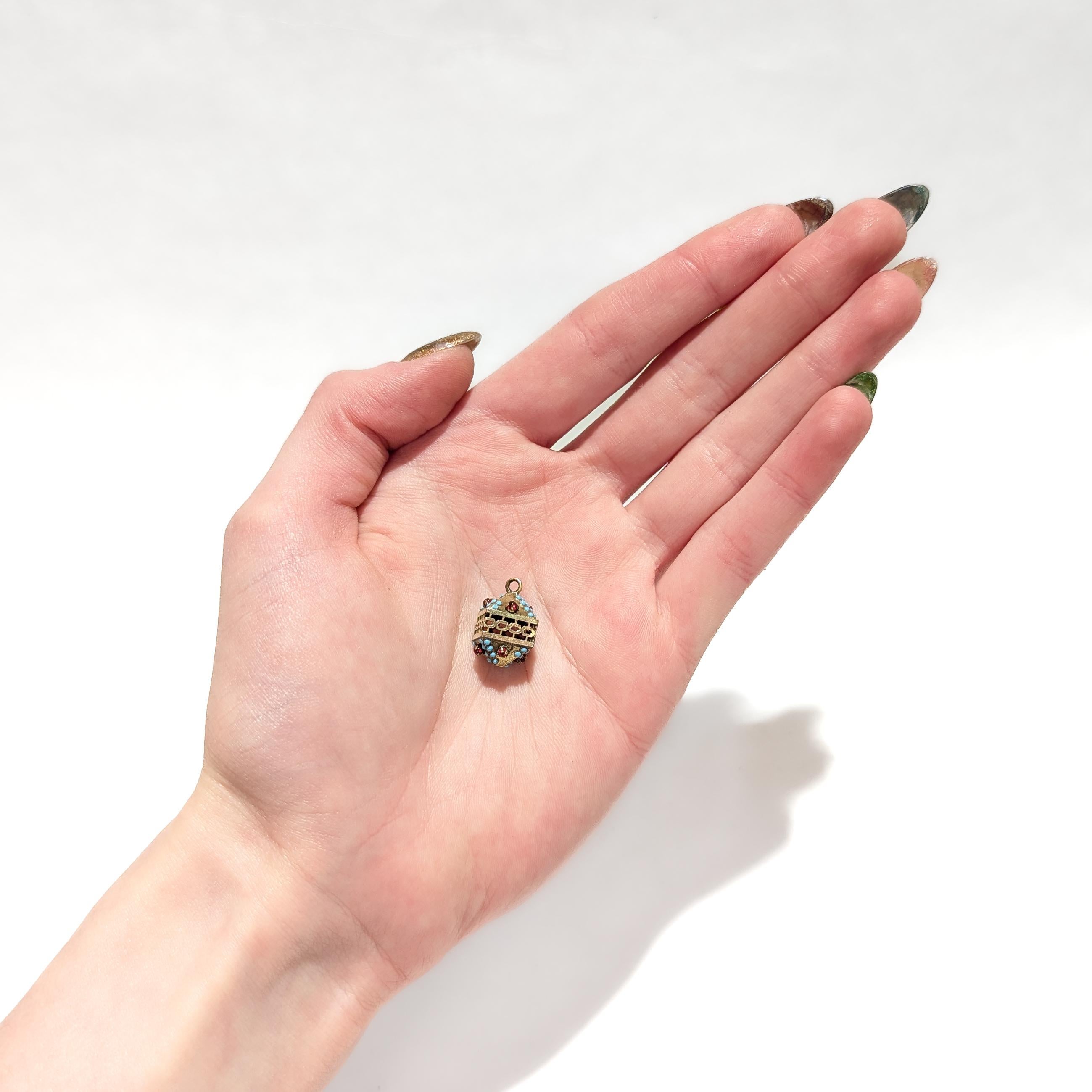 A fine antique gold-filled Aesthetic Movement charm.

With a gold-filled body in a bi-pyramidal shape.

Bezel-set to top and bottom with numerous turquoise cabochons and red glass cabochons. The middle of the charm with geometric openwork.

Having a