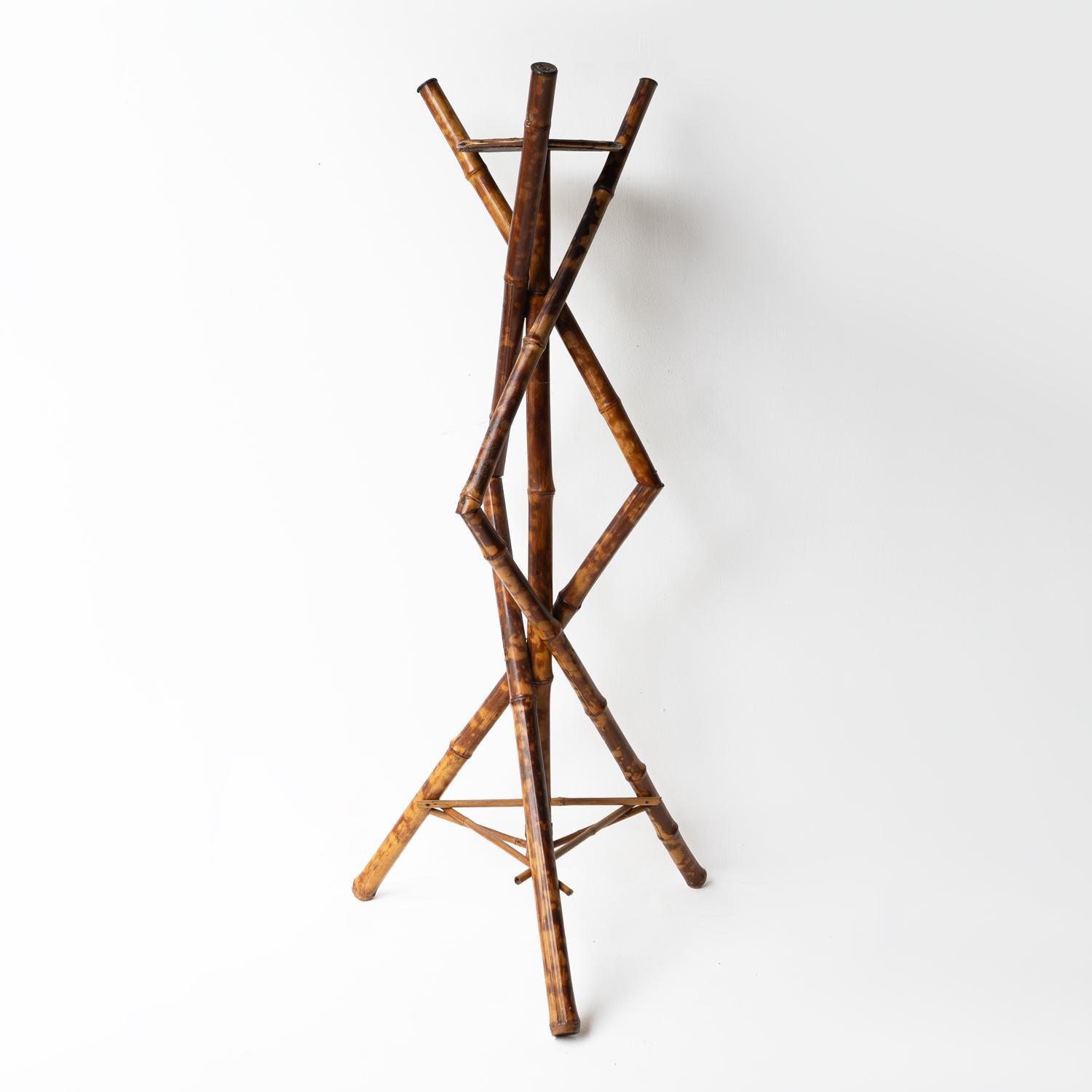 ANTIQUE PEDESTAL PLANT STAND 

A striking silhouette of crisscrossed tiger bamboo creates triangular shapes which terminate in a tripod base.

A central circular platform for a plant or alternative displayed items. 

Dating from the late 19th