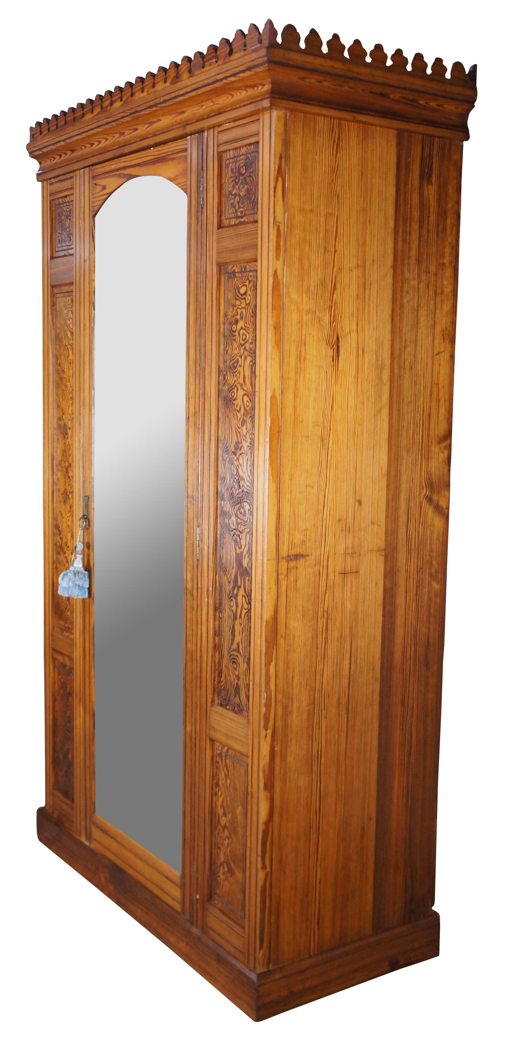 A unique free standing Aesthetic movement wardrobe or closet, circa 1880s. Made from curly pine with a large full length mirror between burled and carved panels. Opens to twelve hooks for hanging garments and jackets with lower concealed storage