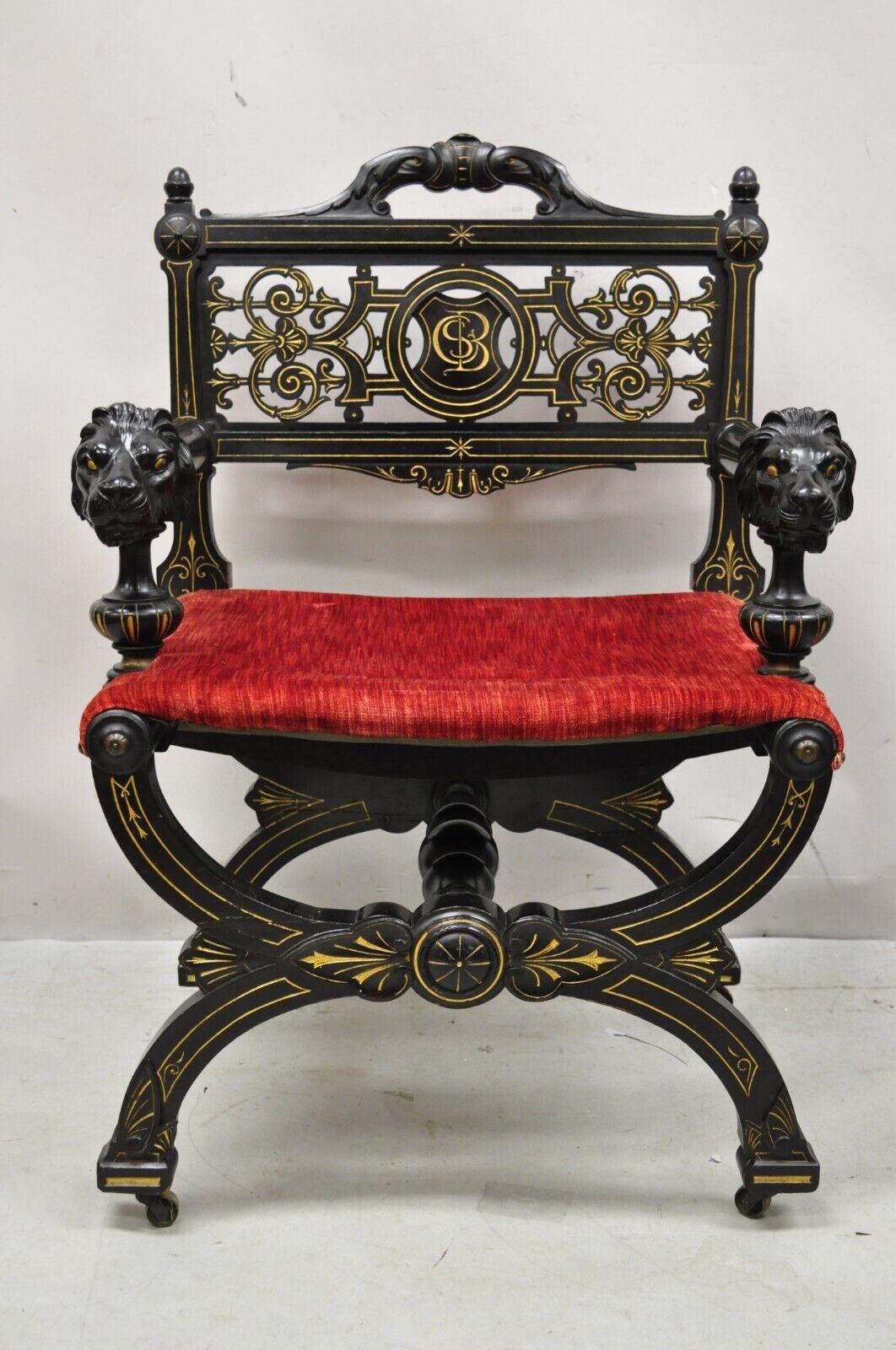 Antique Victorian Aesthetic movement ebonized curule throne arm chair with lions. Item features Lion carved armrests, black/ebonized finish, gold gilt accents, rolling casters, x-form curule frame, red upholstered seat. Very nice antique item.