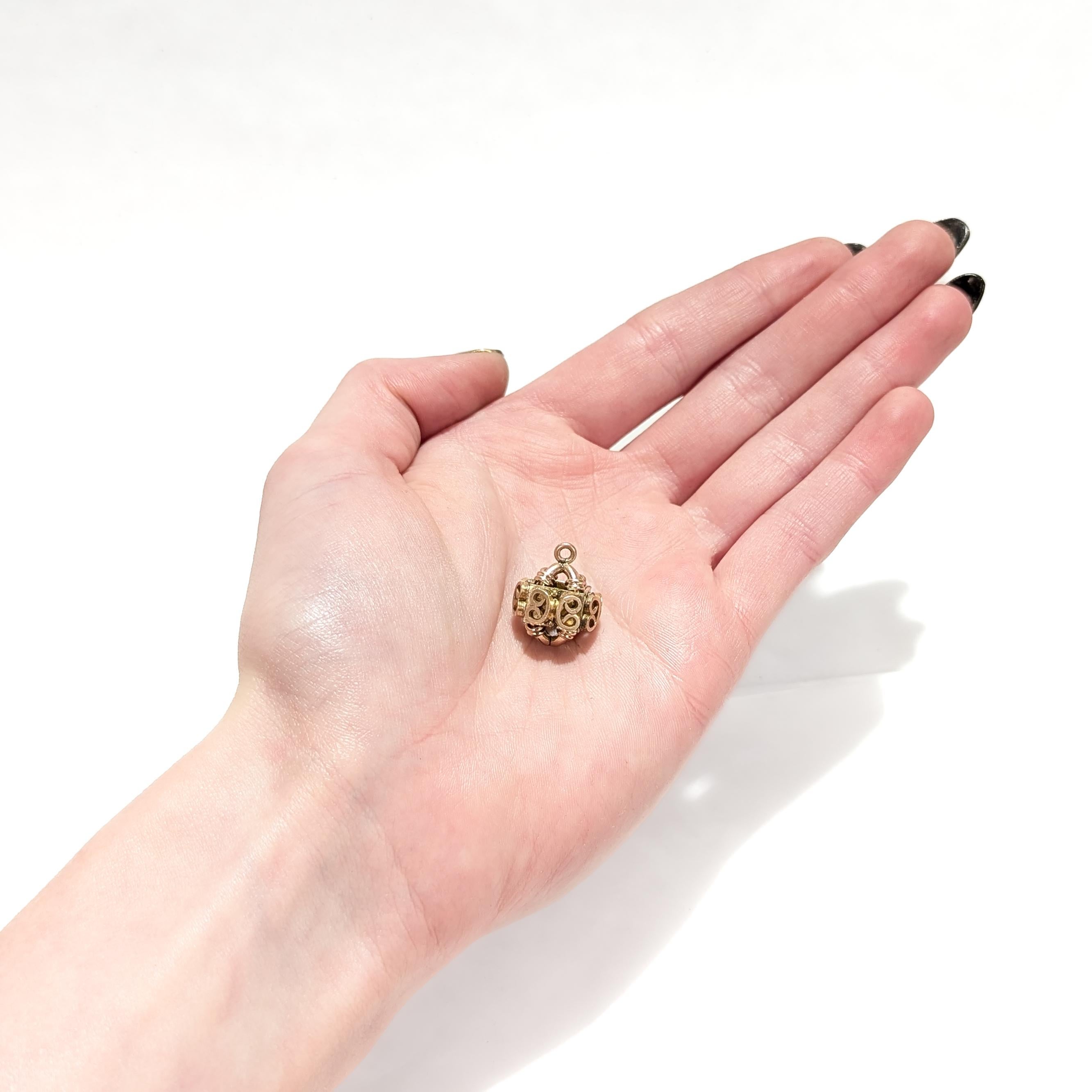 Pendentif ou charme en forme de porte-montre.

Avec un corps architectural rempli d'or.

Avec des cornes de bélier appliquées en fil de fer sur sa circonférence.

Avec un anneau de sécurité ou un anneau de saut intégré et fixe.

Tout simplement un