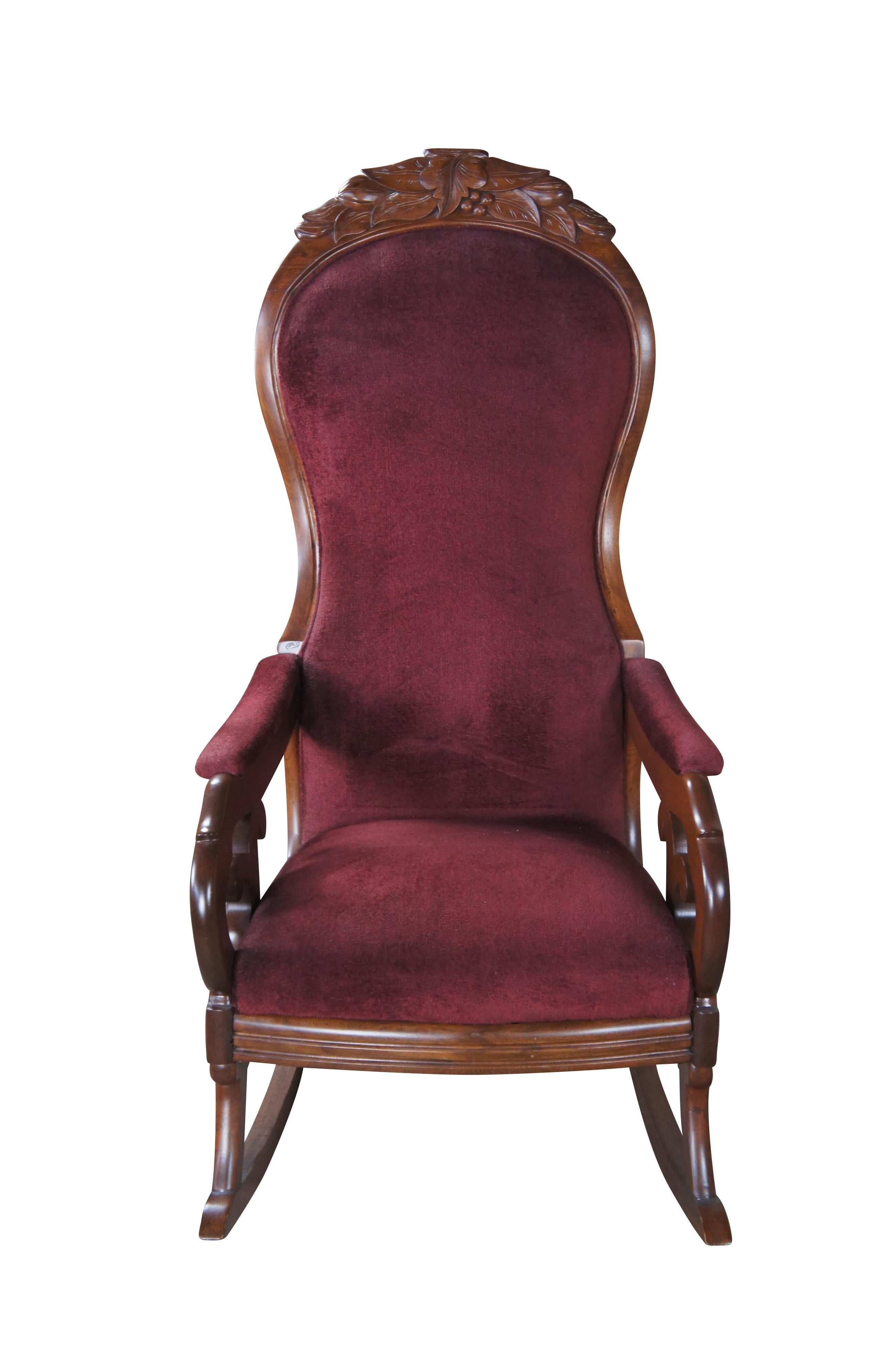 Antique Victorian Aesthetic Movement rocking armchair. Made of walnut featuring serpentine form with velvet / velour upholstery, padded arms, and tall back carved with berry and leaf design.

Attributed to William Roberts of
