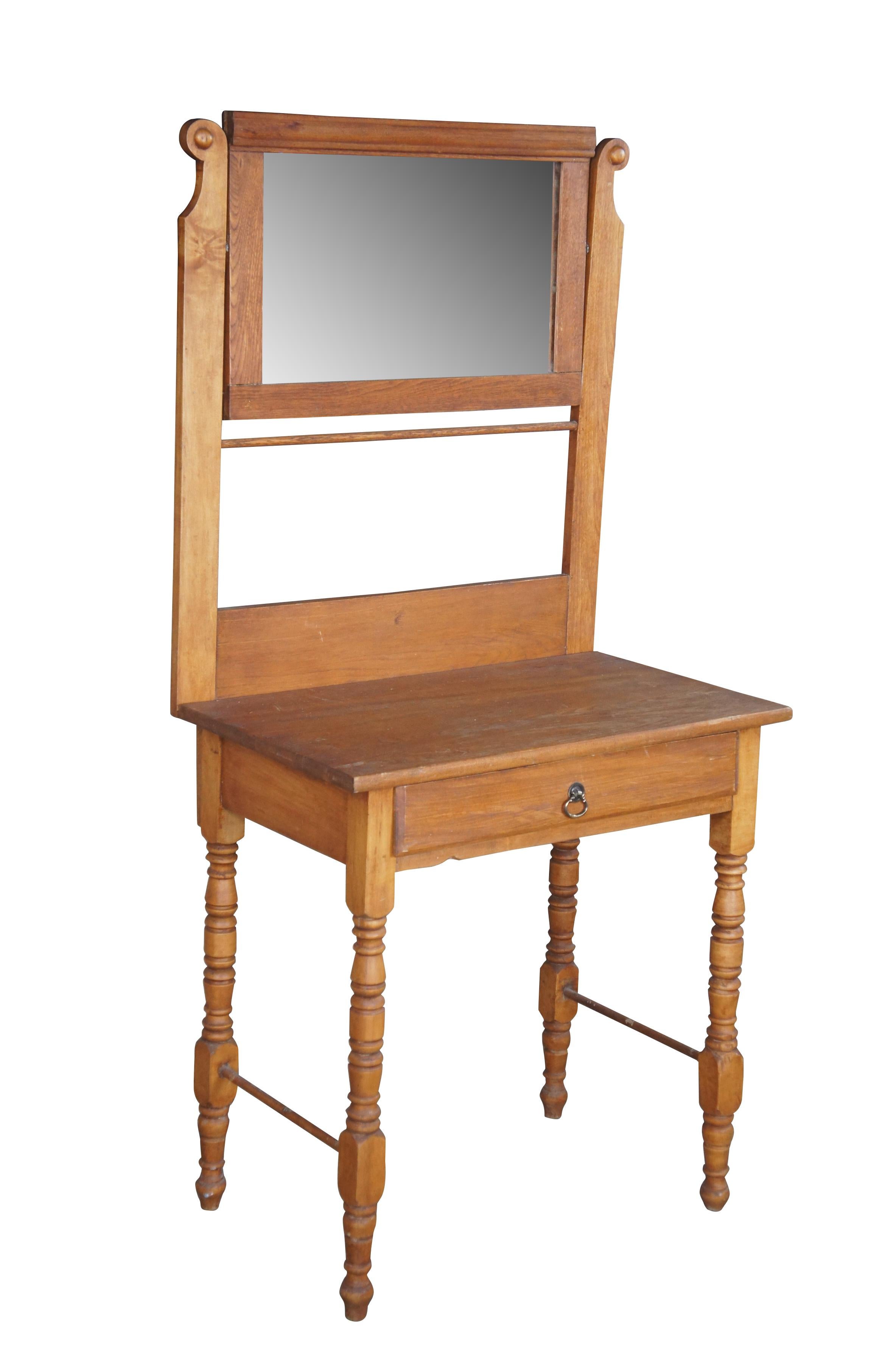 A quaint late Victorian washstand, circa 1900.  Made from oak with a high back featuring a swivel mirror and towel bar.  The base has one interior shelf with brass pull and is supported by turned legs.

Dimensions:
57