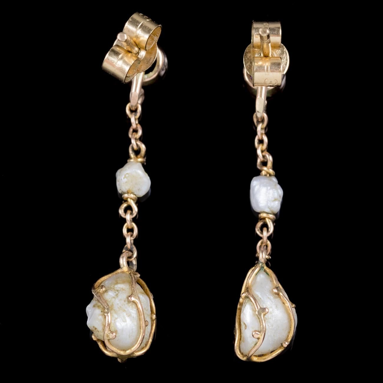 A fabulous pair of antique Victorian drop earrings featuring cage set Baroque Pearls hanging from a gold chain crowned with a 0.10ct Amethyst. Baroque Pearls have a wonderful lustre with a rich creamy tone and are unique for their irregular