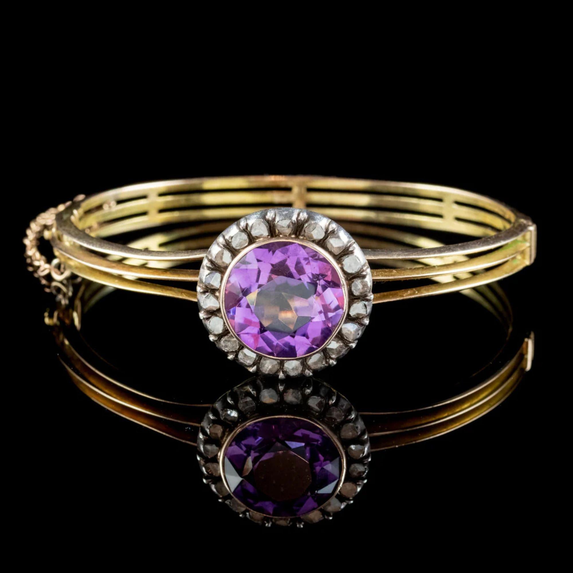 A regal Antique Victorian bangle from the late 19th Century. The band is made up of three separated 15ct Yellow Gold bands and crowned with a Silver gallery with a magnificent Amethyst on top weighing approx. 10ct with a glistening halo of Rose cut