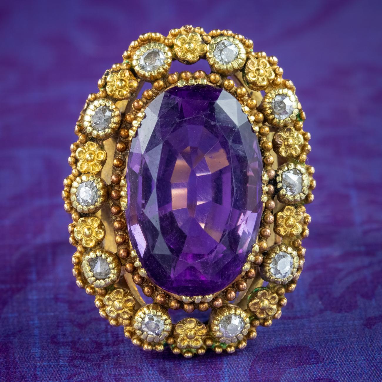 An impressive antique Victorian statement ring built around a large oval cut amethyst in the centre, weighing approx. 7.2 carats. It has a deep, regal purple hue and is framed in an ornate, cannetille style gallery encircled with gold beading,