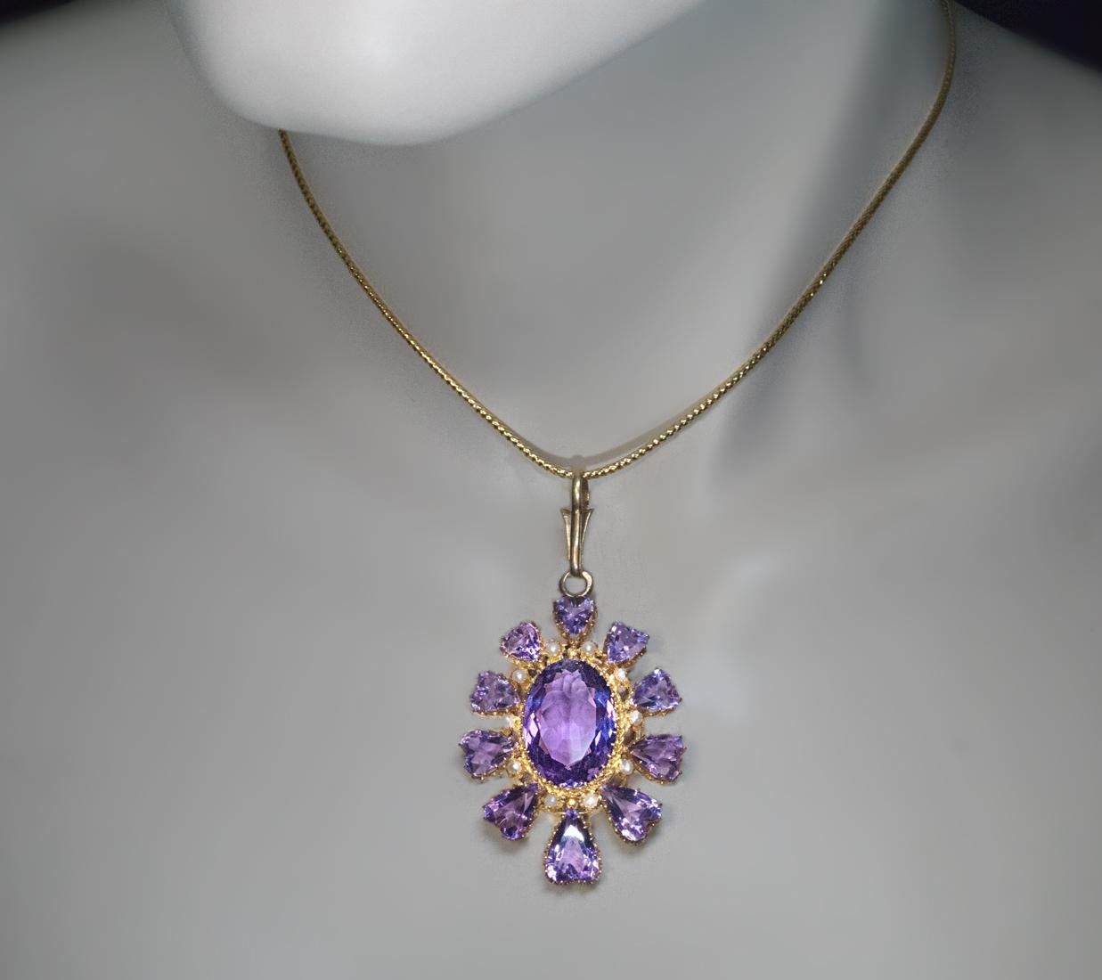 Circa 1870s-1880s

This vibrant antique 14K gold pendant features sparkling lavender purple amethysts. It is centered with an oval amethyst, accented by small half pearls, and  surrounded by ten heart-shaped amethysts which graduate vertically in