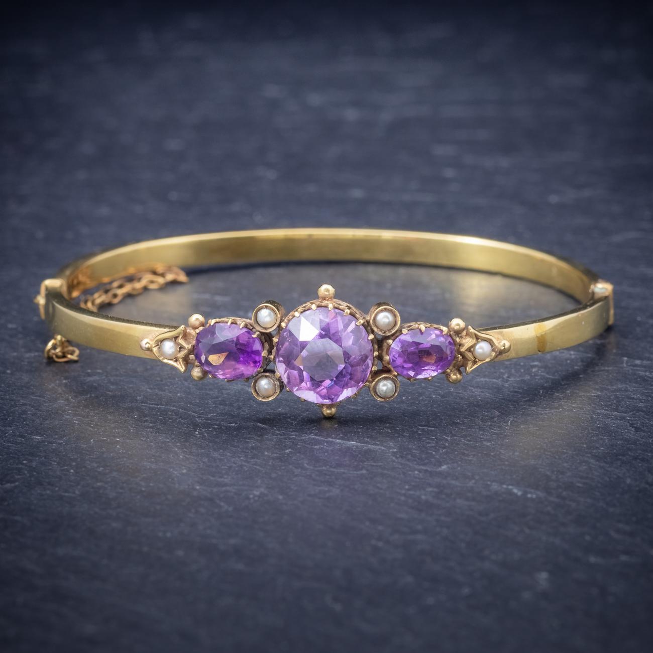 A fabulous antique Victorian bangle adorned with Pearls and a trilogy of beautiful Amethysts the largest of which is 4ct flanked by smaller 3ct stones. The bangle is fashioned in 9ct Yellow Gold and fitted with a safety chain on the clasp. It looks