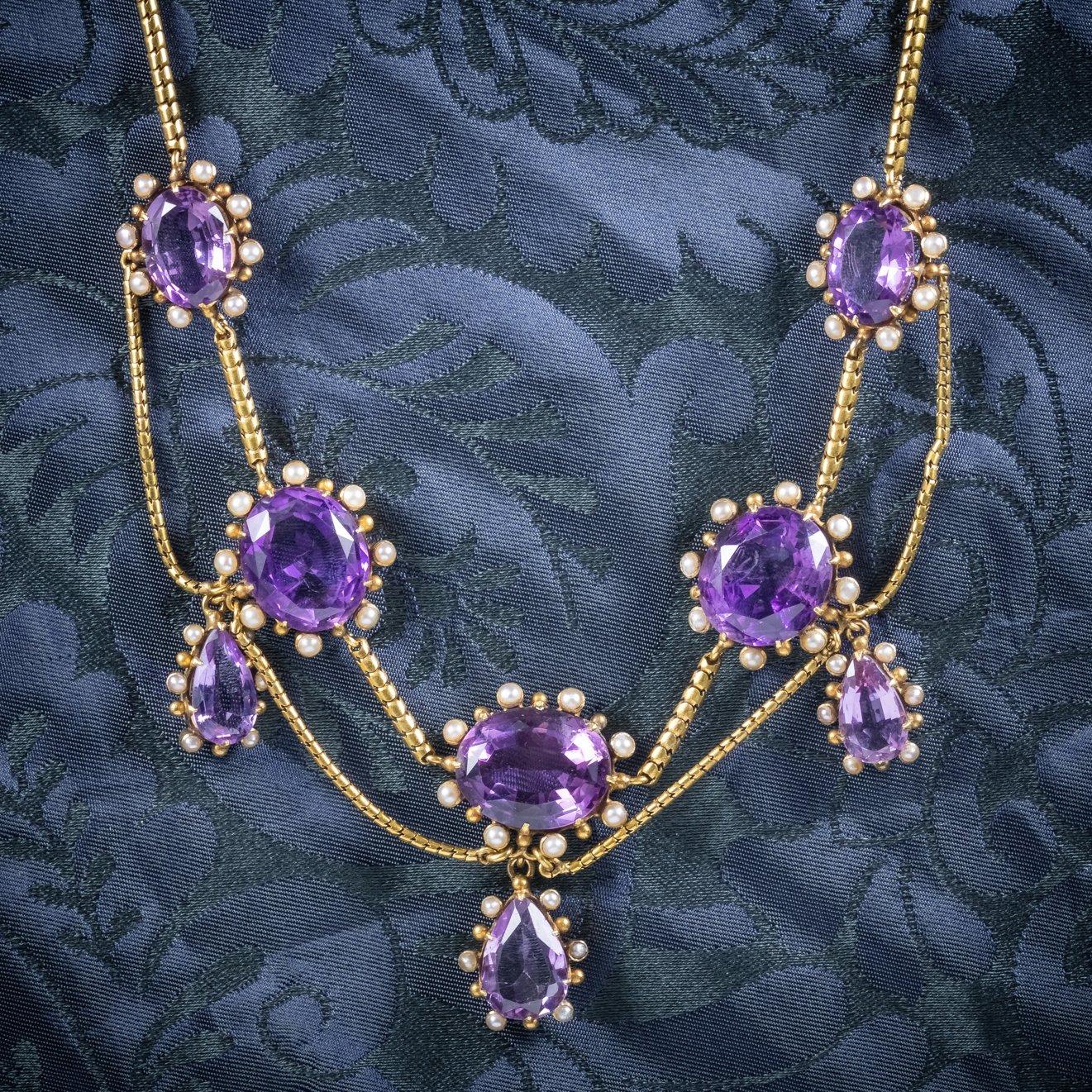 A stunning antique Victorian garland necklace (C.1860), adorned with approx. 60ct of beautiful, deep purple Amethyst, encircled by natural Pearls.

Five lovely, oval Amethyst dangle from a festoon chain leading to three teardrop Amethyst droppers.