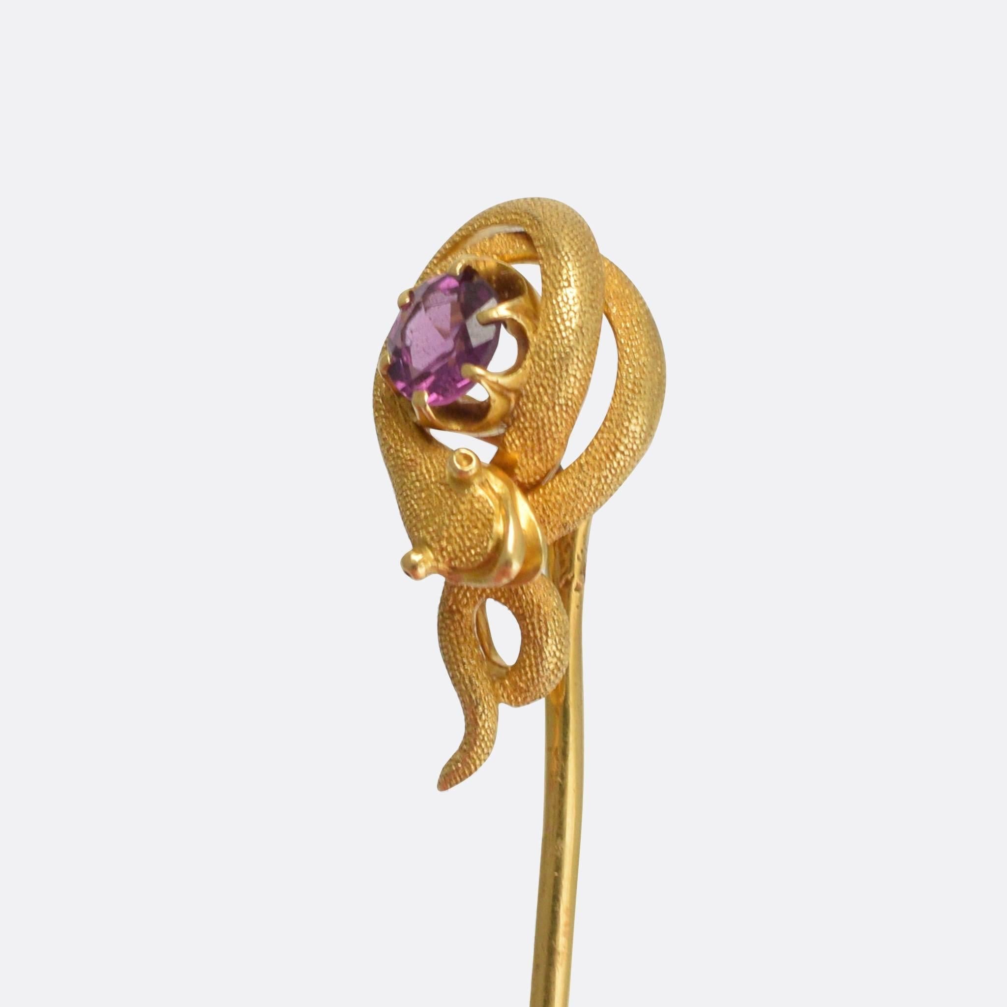 A cool antique stick pin, the head modelled as a snake, coiled around a faceted amethyst. The goldwork is particularly well executed, with beautiful textured skin and a cartoon-like face. Modelled in 18k gold throughout.

STONES
Natural