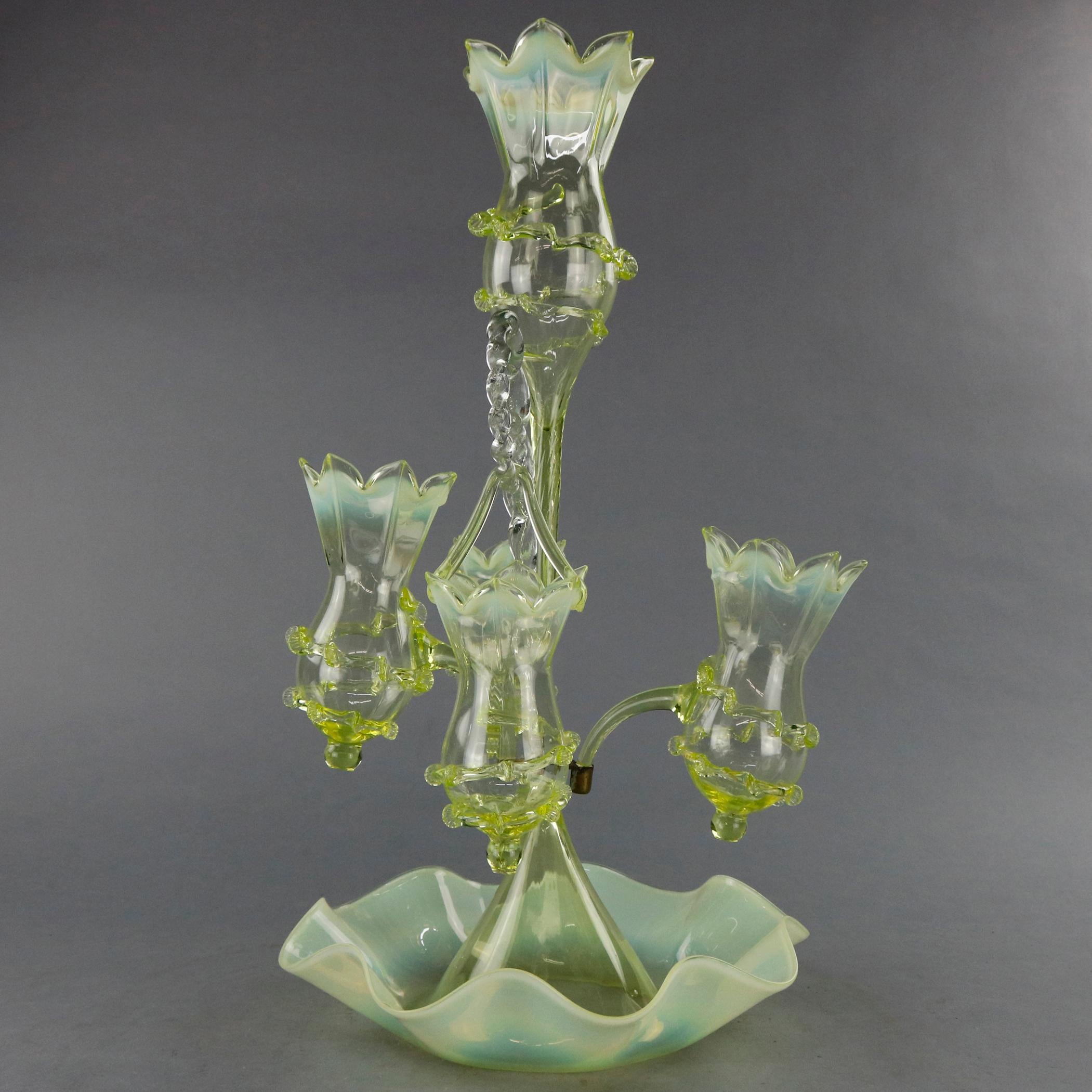 An antique Victorian epergne centerpiece offers vaseline glass construction with floral form hanging and fixed vases (vessels) with applied string decoration on conical base with ruffled rim, circa 1890

Measures: 23.5