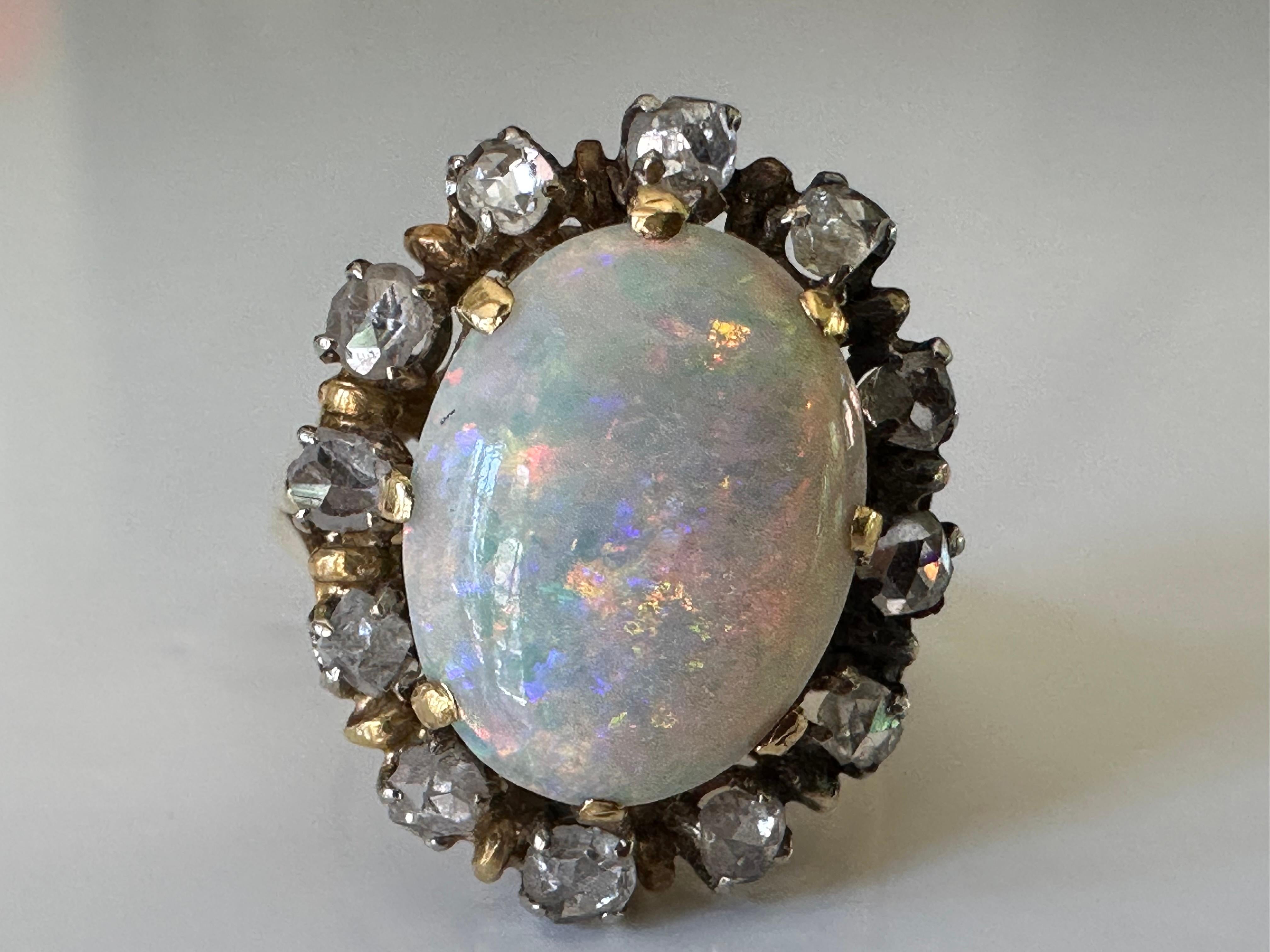 A 3.0-carat luminous Australian opal with iridescent hues of blue, green, yellow, orange and pink centers this exquisite antique ring surrounded by a halo of 0.85 carats of rose-cut diamonds. Set in 18K yellow gold.  Circa mid-to-late-19th century.