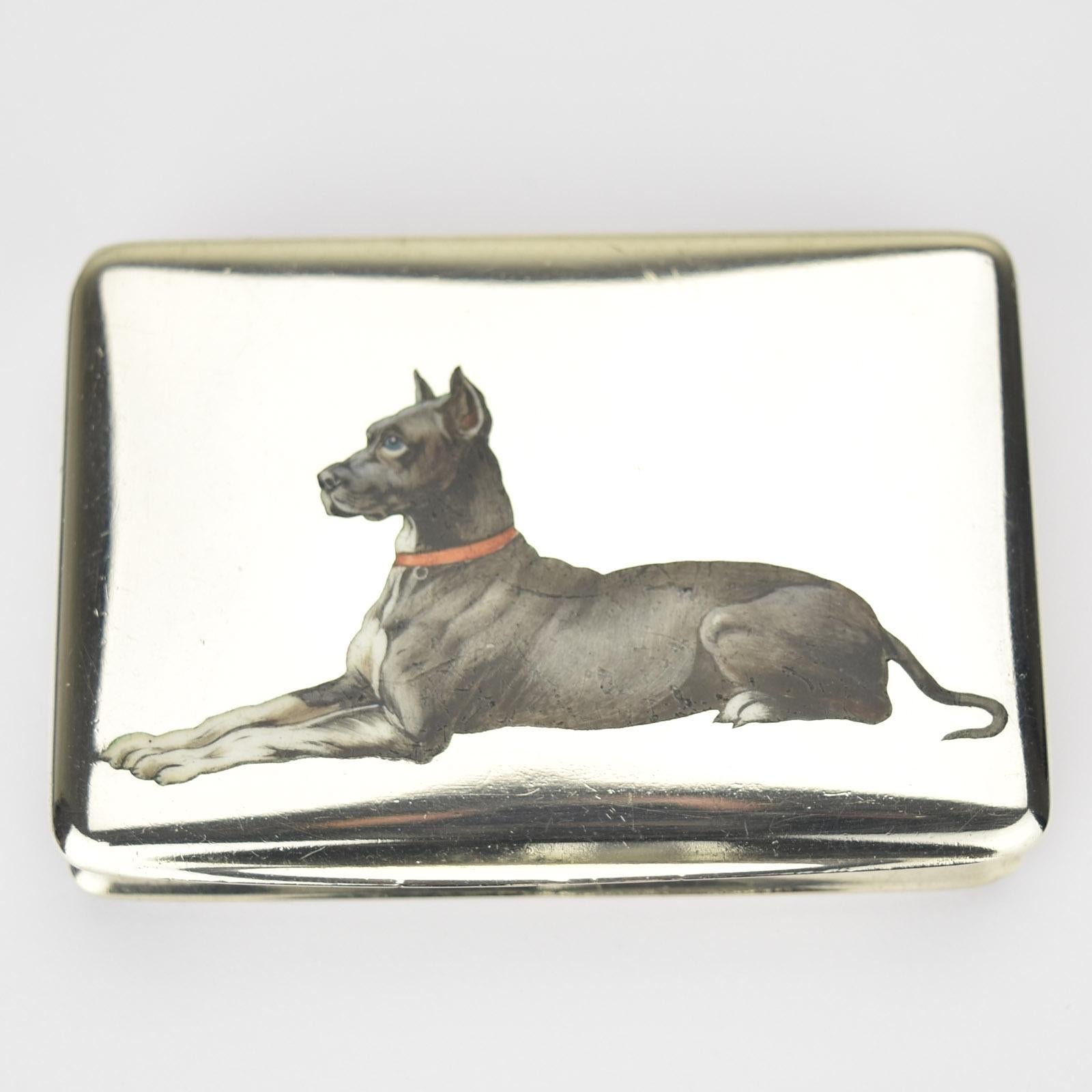 Belle tabatière ou boîte à pilules naturaliste en émail peint à la main représentant un chien dogue allemand, probablement fabriquée autour de 1900 en Autriche. La boîte est en argent 0.800 avec intérieur en vermeil.

Dimensions : environ