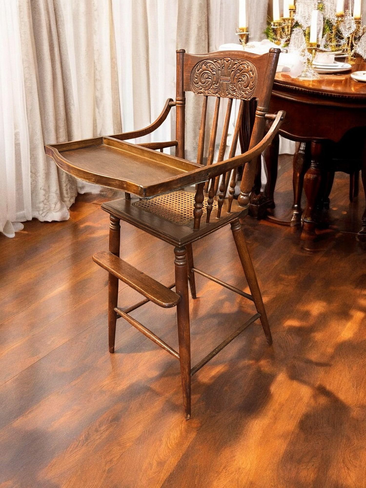 An Antique Victorian Era Baby High Chair, a charming and authentic piece that harks back to a bygone era. This high chair carries numerous exquisite details, such as the cane seat, intricately carved backrest, and classic spindles, which showcase