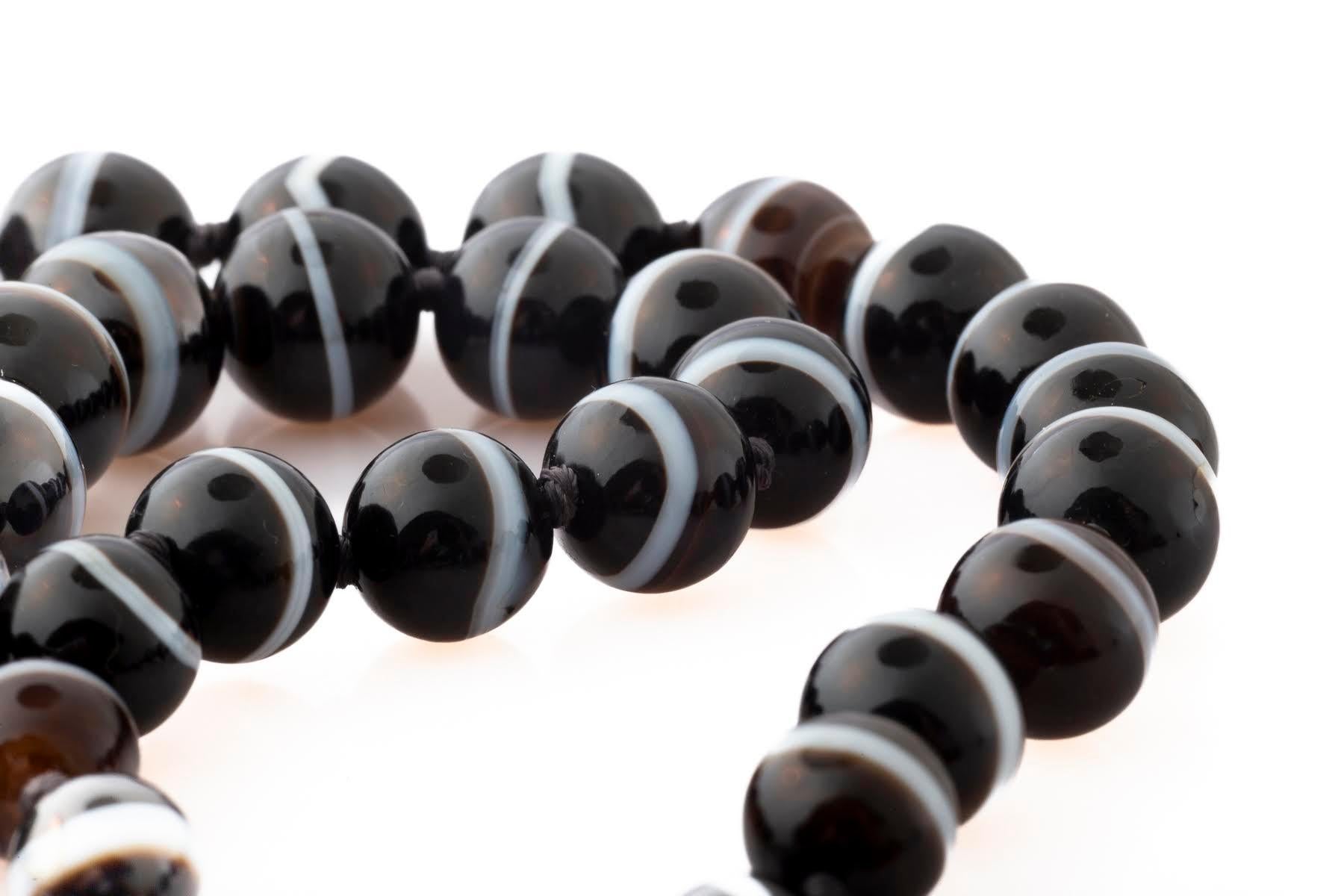 Les colliers victoriens en perles d'agate sont rares. Ce brin est en excellent état. Les perles d'agate sont nouées. Il s'agit d'un cordon gradué dont la taille varie de 1,9 cm à 0,9 cm. La plupart des agates noires avec quelques tons chocolat et