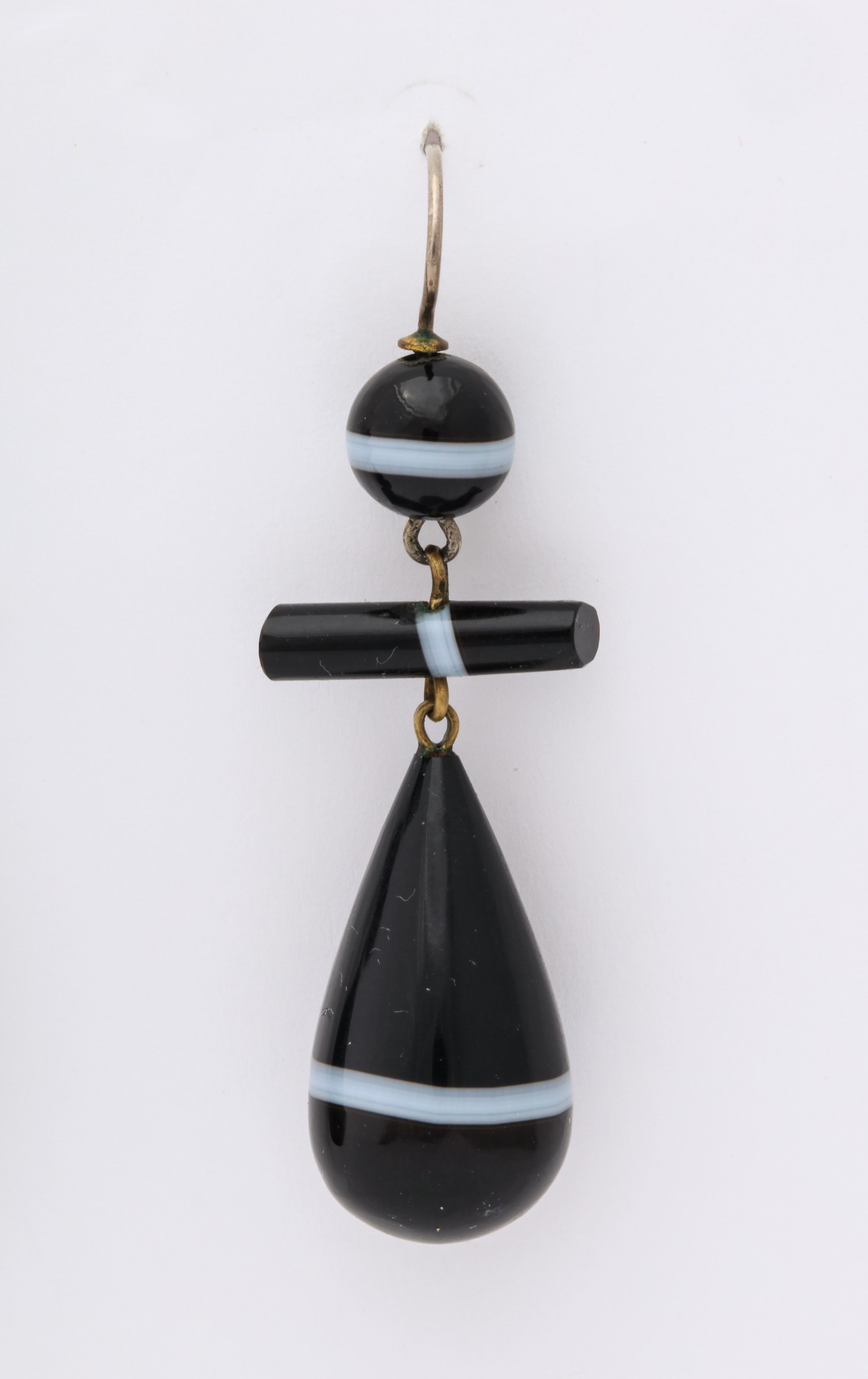 Striking in contrasting color and in their geometric form, the teardrop banded agate earrings originated in England c.1860. When well made, the stone cutter choses parts of the agate that he can shape so that the white band is in the same place in
