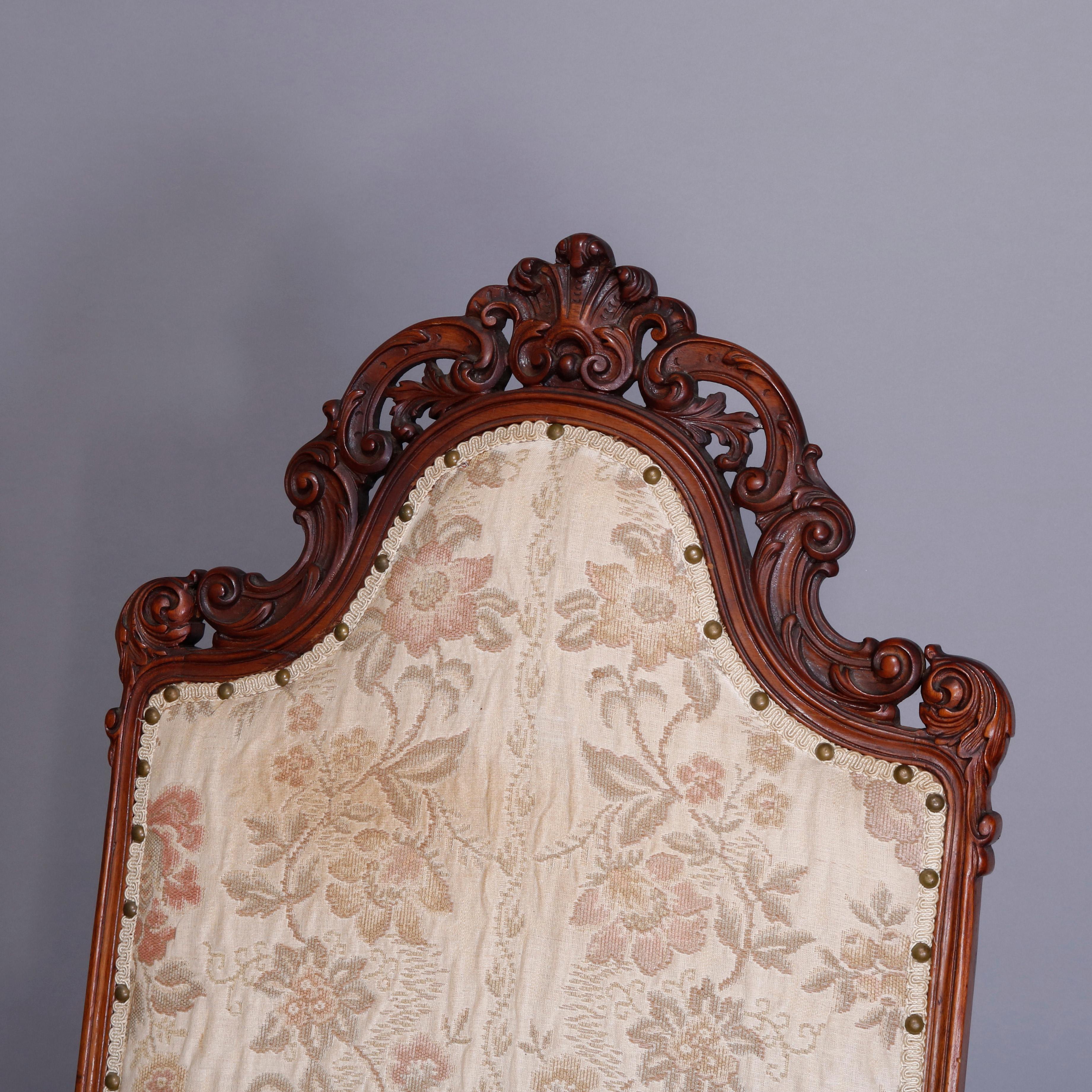 An antique Victorian Baroque style figural throne chair offers carved walnut frame with tall back having pierced scroll and foliate crest surmounting upholstered back and seat with arms terminating in carved lion heads, apron with carved and pierced
