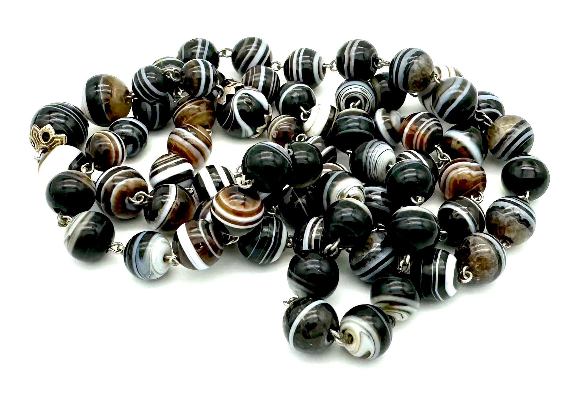 Questa collana è composta da sessantaquattro perline di sardonice. Le perline sono ben assortite, due sono più grandi delle altre sessantadue. Le perle di agata a fascia sono collegate da maglie ornamentali in filo d'argento. Le due perle più grandi