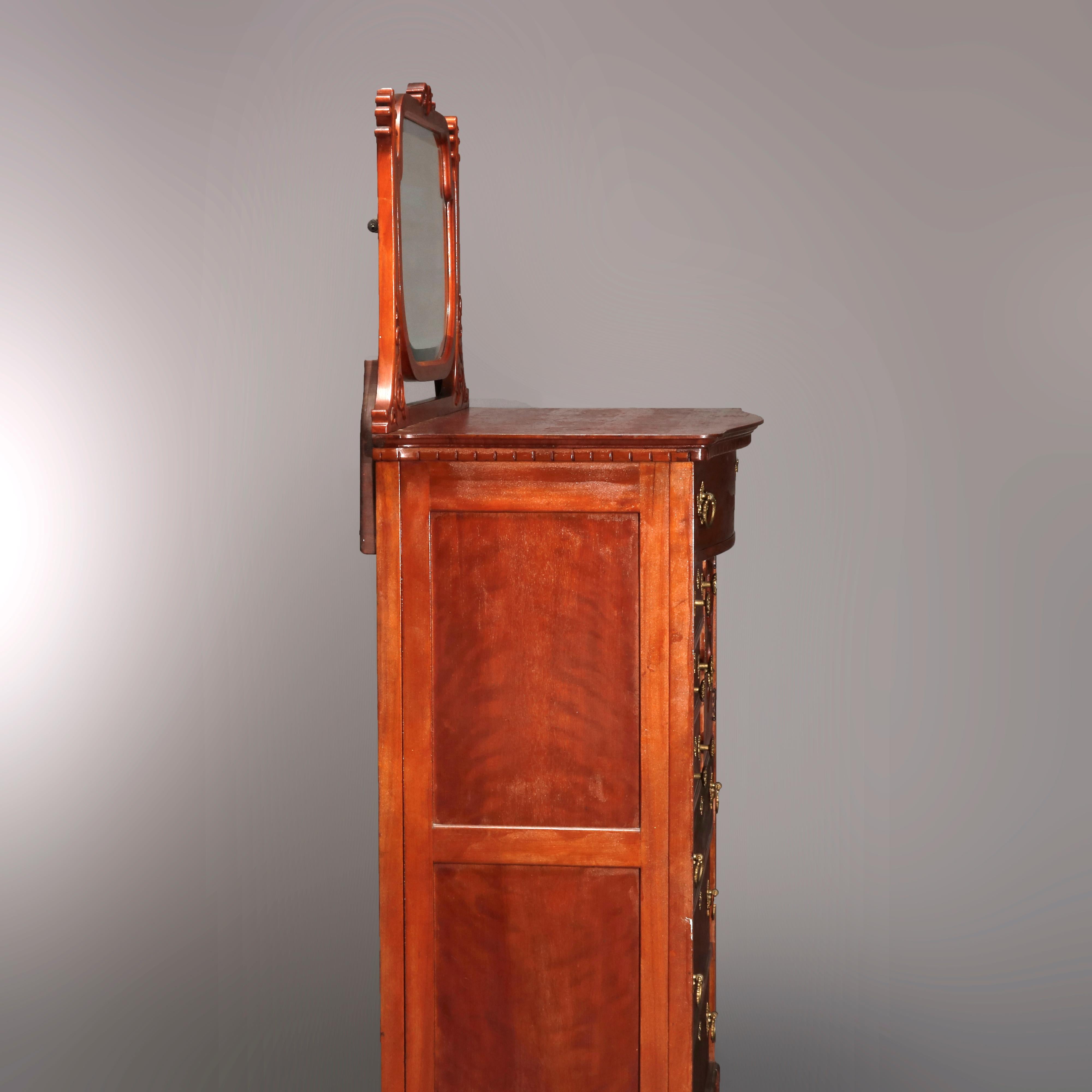 An antique Victorian chiffonier chest offers birch construction with shield shaped mirror having carved foliate d=crest and flanked by stylized palmette supports surmounting chest with bow front frieze drawer over bonnet case having carved scroll