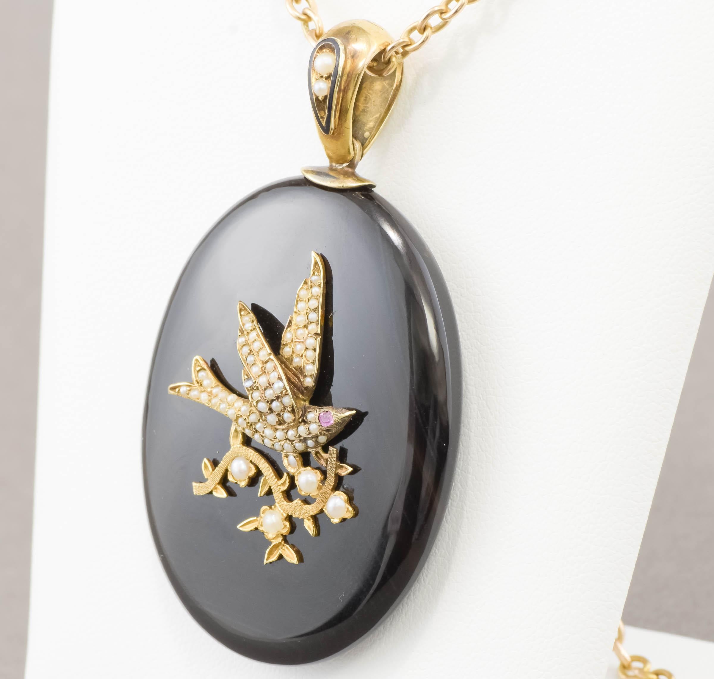 Offered is a very charming Victorian period onyx locket, featuring a pearl set gold Bird (a Swallow) with a foliate design.  The locket retains its original enameled and pearl-set bail, as well as the frame and glazing to the locket back.  This