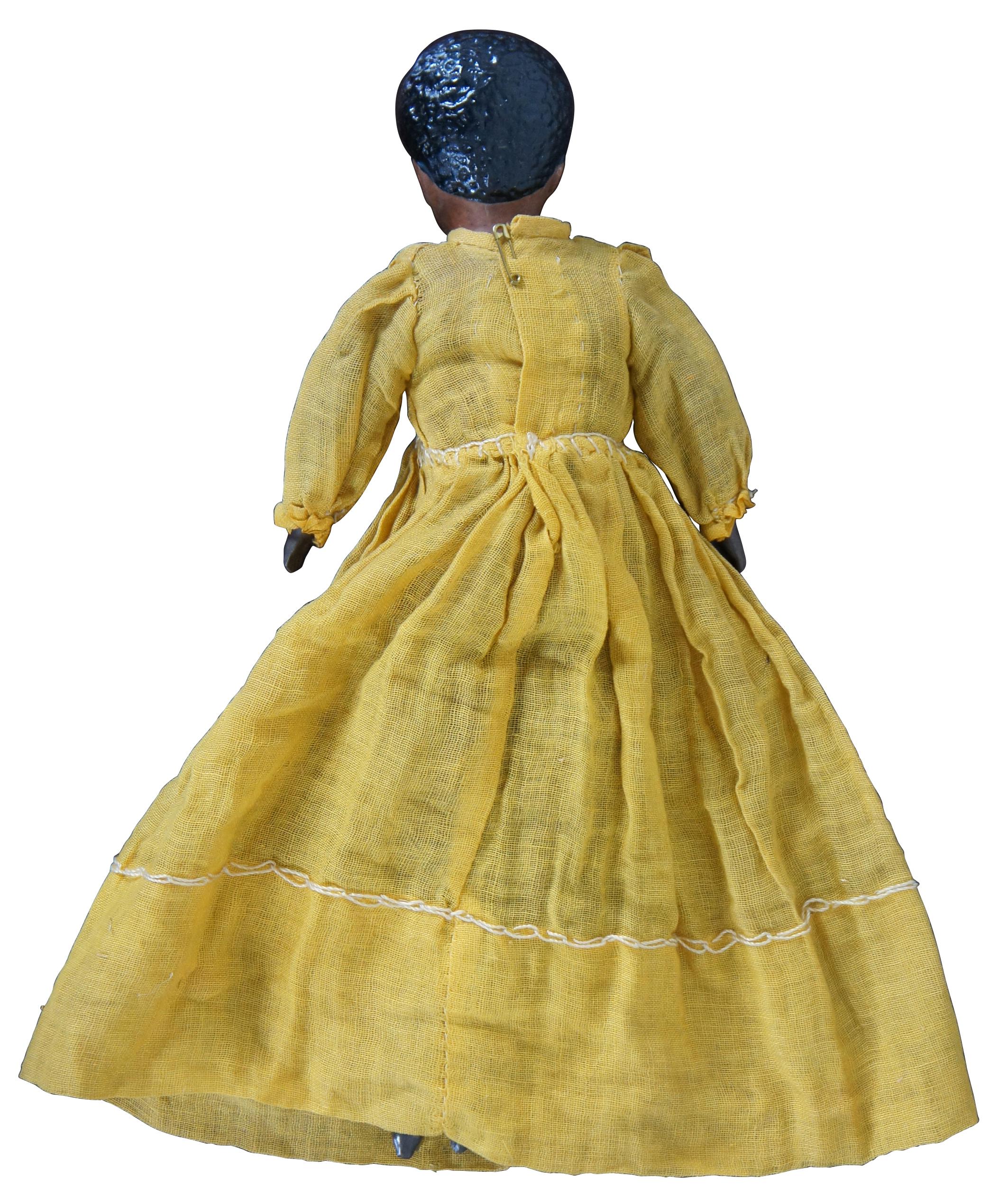 Unique antique 19th century African American (possibly mulatto?) doll with bisque head and hands, molded boots and cropped hair style, and a cloth body dressed in a yellow dress.