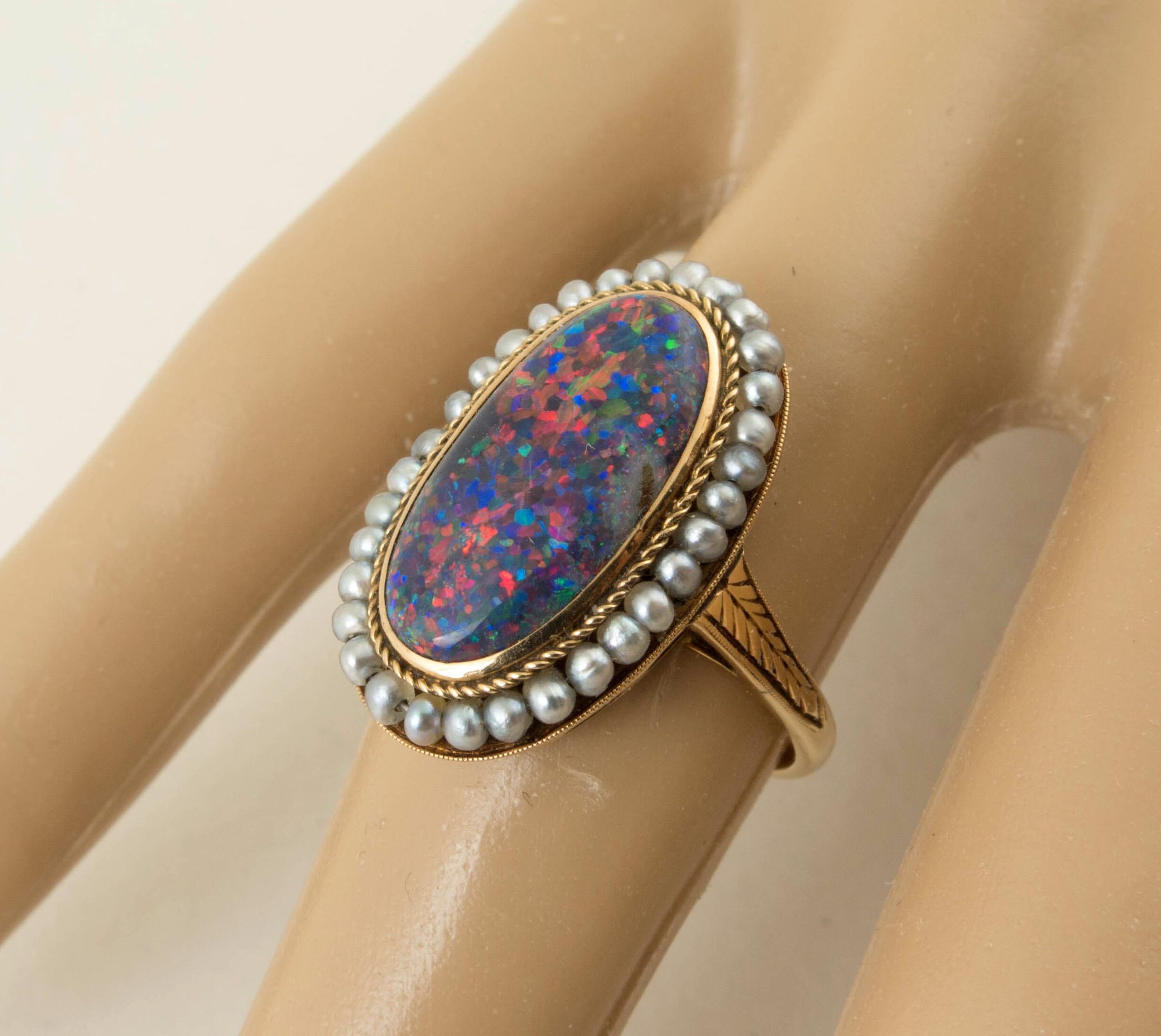 A beautiful late Victorian black opal and natural seed pearl gold ring. The black opal is approximate 2 carat oval cabochon cut pinfire black opal with predominant red color. Pinfire pattern with red/ violet/cyan/green. There are 32 natural seed