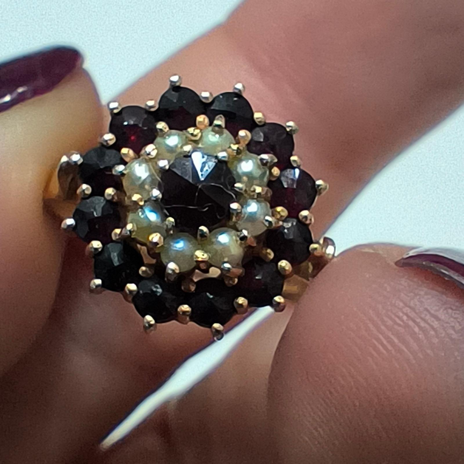 Anello da cocktail vintage con granato e perle di seme - Argento placcato oro, disegno floreale a grappolo
Questo anello da cocktail vintage, elegante e drammatico, presenta un granato rosso intenso al centro, circondato da un'aureola di perle