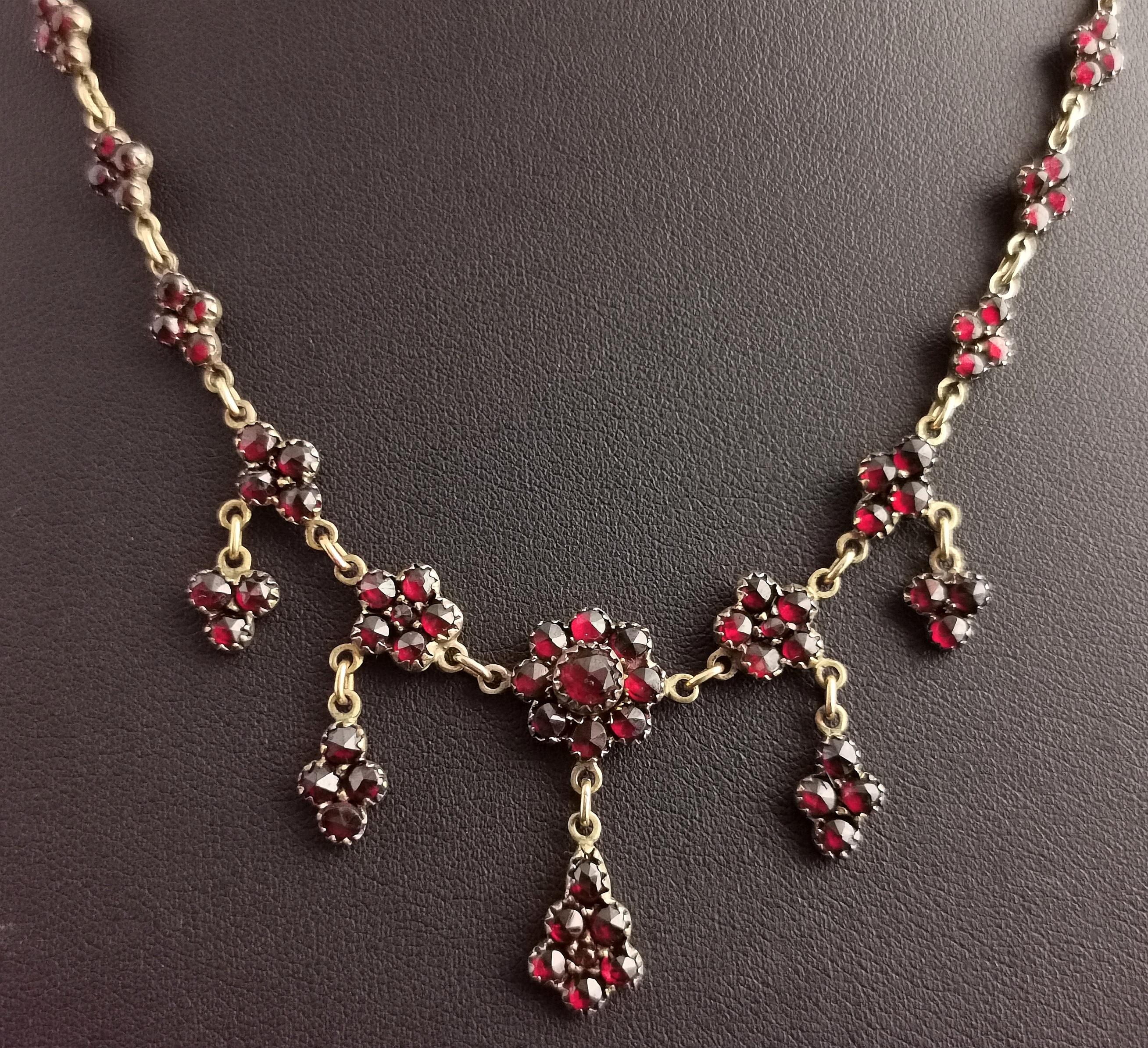 A truly stunning antique, late Victorian era Bohemian garnet drop necklace.

It is adorned with rich deep red bohemian garnets with mixed cuts, the top links are shaped like quatrefoils and adjoined with gold chain links.

The necklace has a festoon