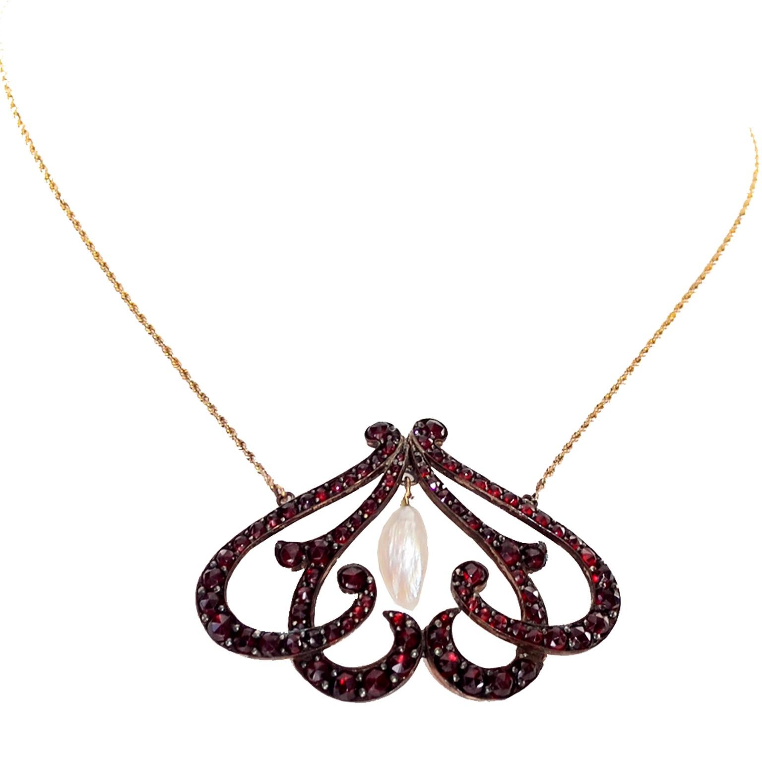 This is a lovely Victorian era bohemian garnet necklace that has a very unique flourish pendant with single pearl drop in the center. The pendant is attached to a gold filled chain. The necklace has an insert clasp and the pendant measures 1.5