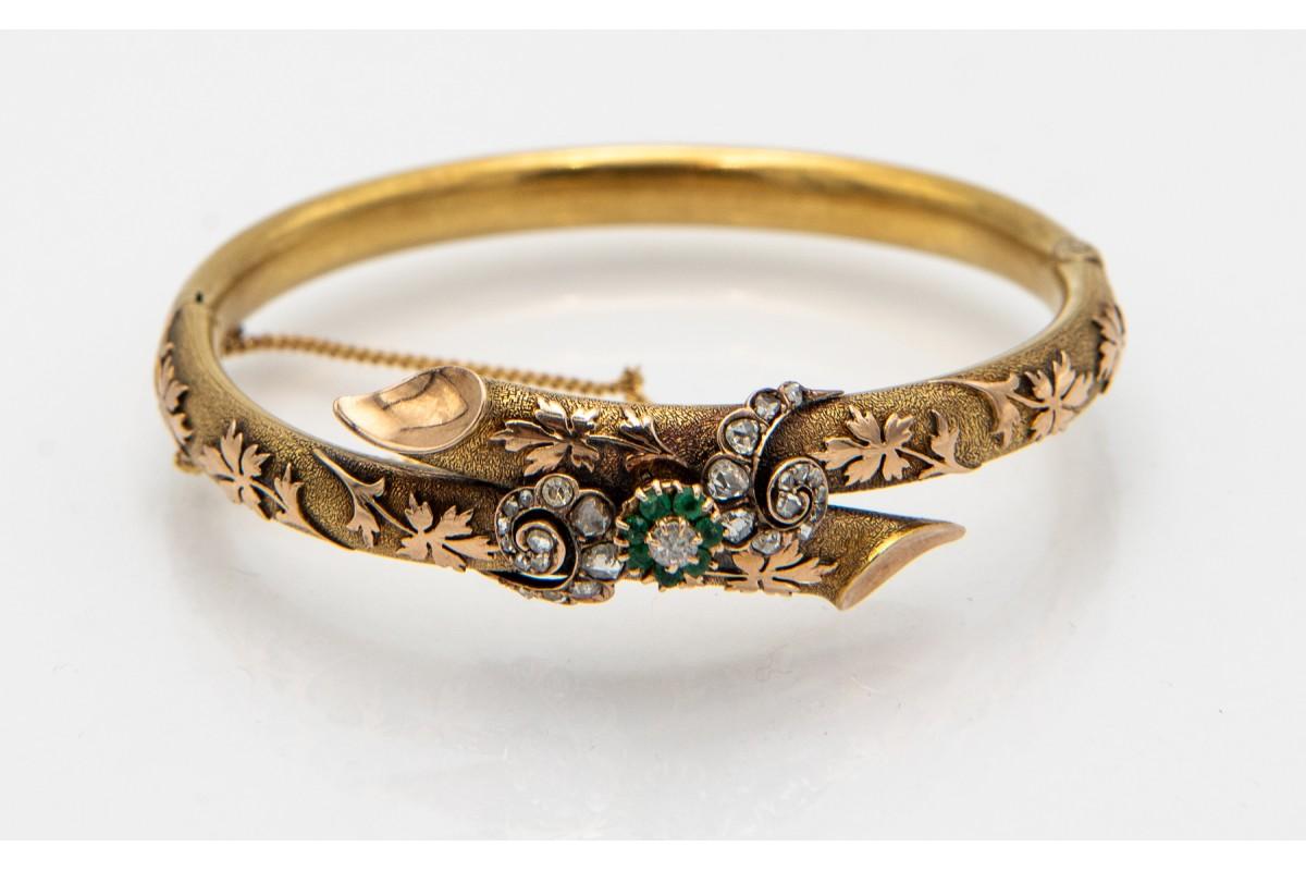 Antique Victorian bracelet with emeralds and diamonds made of 0.750 yellow gold. The hoop is made in the form of a relief with plant motifs, fastened with a buckle with a safety chain. Decorated with 27 diamonds in old rosette cuts and 8/8 with a