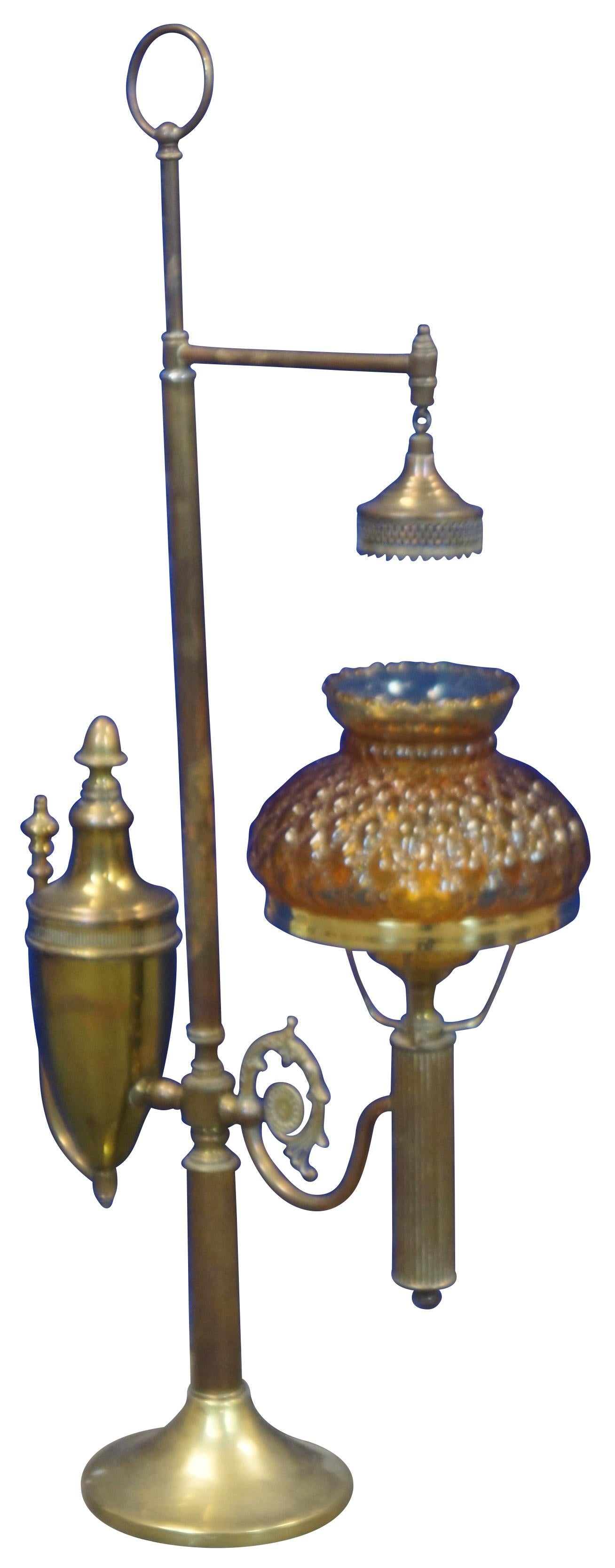 Antique Victorian period converted electric student lamp that originally burned oil or kerosene from a font off to the side to allow light down onto a desk. Features a brass body with a quilted hobnail amber glass shade. Measure 31