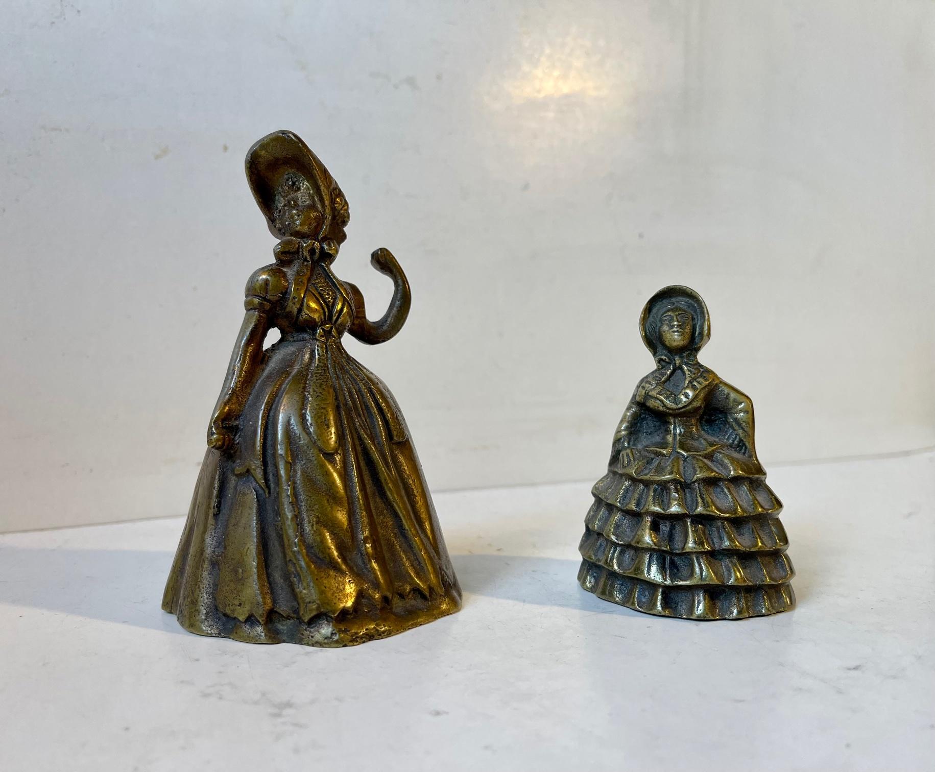 A couple of cast table bells in the shape of fashionable ladies. The little one showcases a Crinoline dress. They were both made in England during the 1860s. Despite their size of 12.5 and 8.5 cm they are rather heavy made from thich stocks brass.