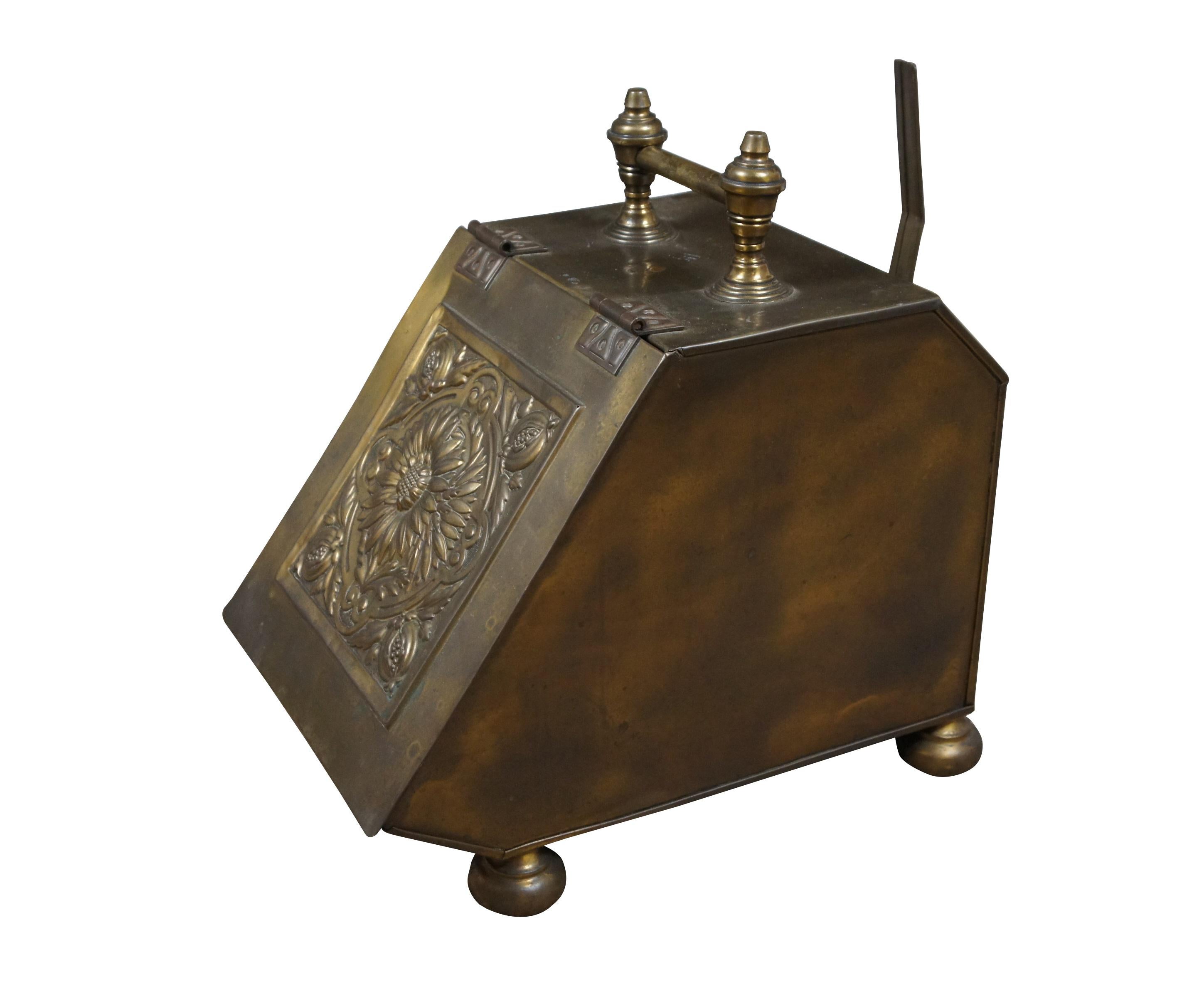 Antique Edwardian / Victorian / Aesthetic Movement brass coal scuttle and shovel. Low rectangular form with slanted front / lid, embossed with a motif of daisies / sunflowers framed in a quatrefoil and pomegranates. Fixed handle on top; bun feet;