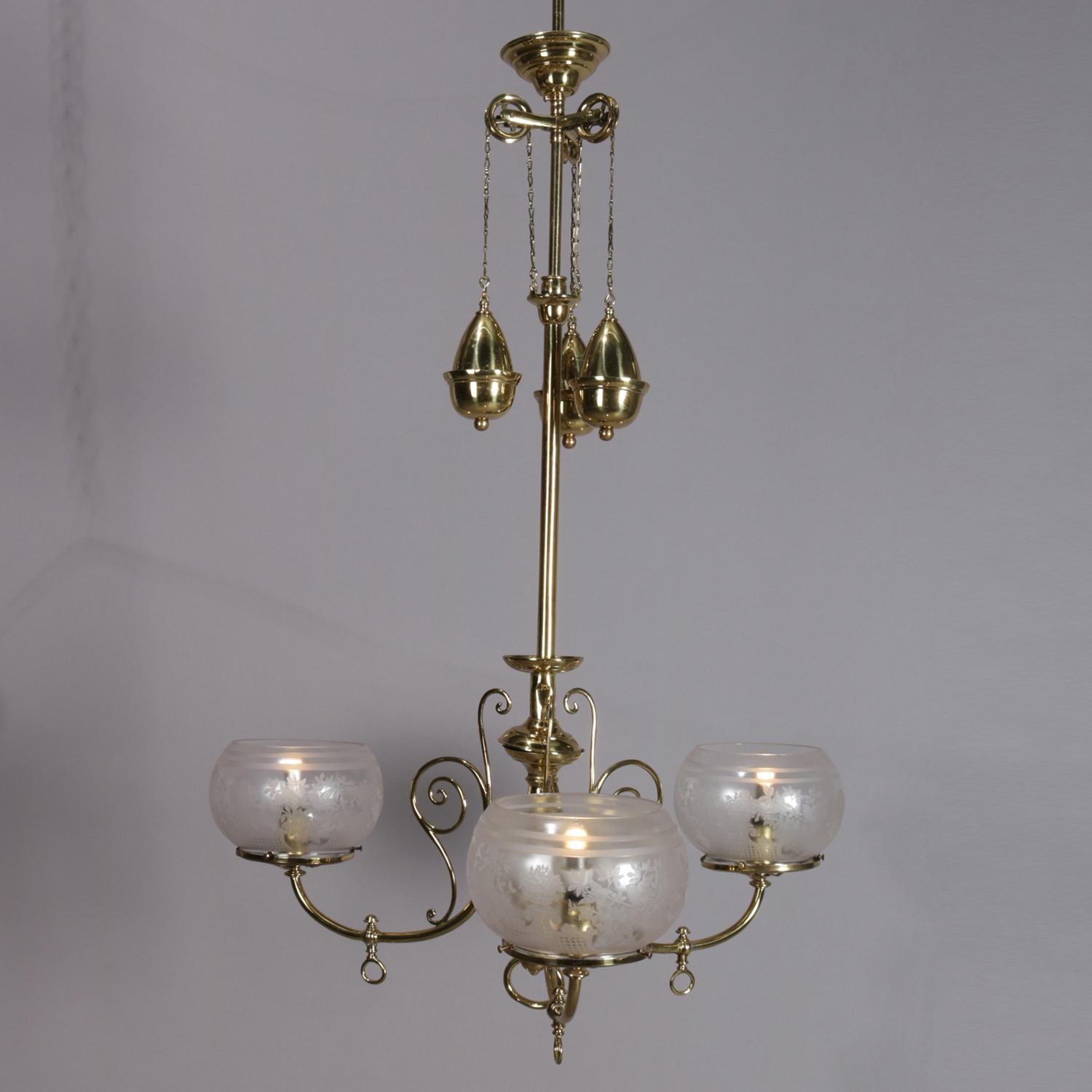 Antique Victorian electrified gas chandelier features brass frame with three c-scroll arms having scroll decoration and terminating in foliate etched bowl form glass shades, weight driven height adjustment, circa 1900

Measures: 44