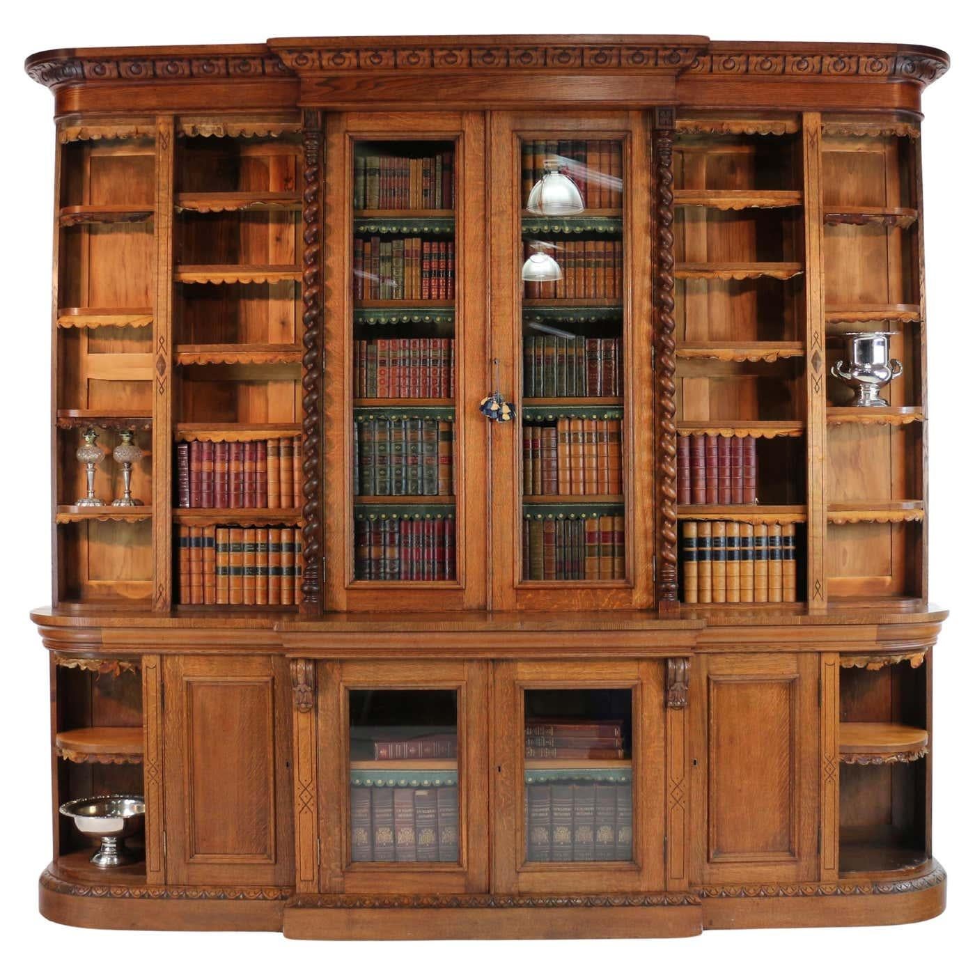 An impressive Victorian quarter sawn oak breakfront bookcase featuring curved sides and barley twist columns and formally part of the furnishings of Kellie Castle, Fife, whilst home of the Lorimer family.   The foliate carved cornice above two