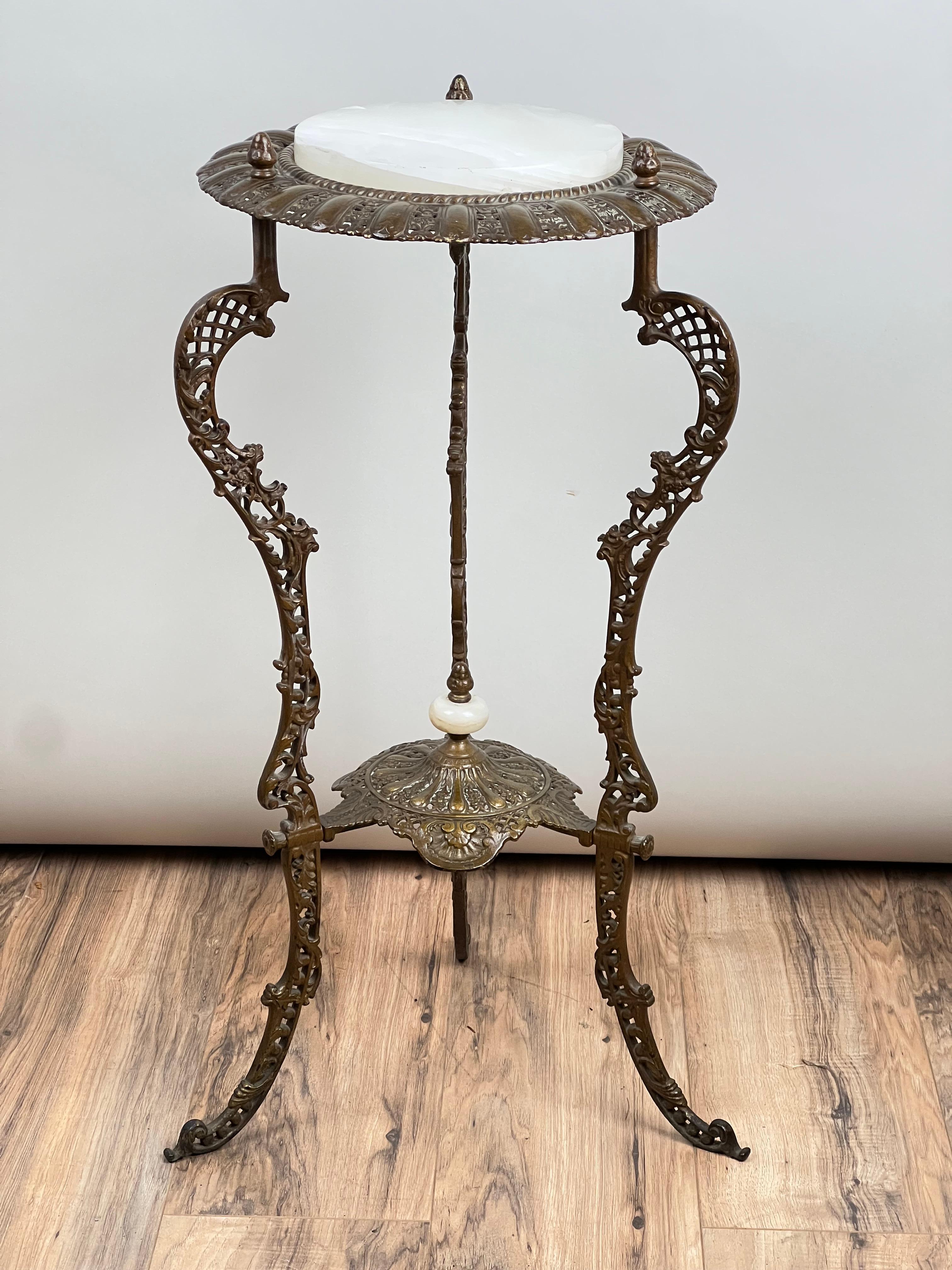 Ce joli stand victorien de la fin du XIXe siècle est un exemple élégant du travail du métal orné et des matériaux raffinés en vogue à cette époque. Fabriquée en bronze moulé avec des pieds joliment percés et enroulés, cette pièce met en valeur le