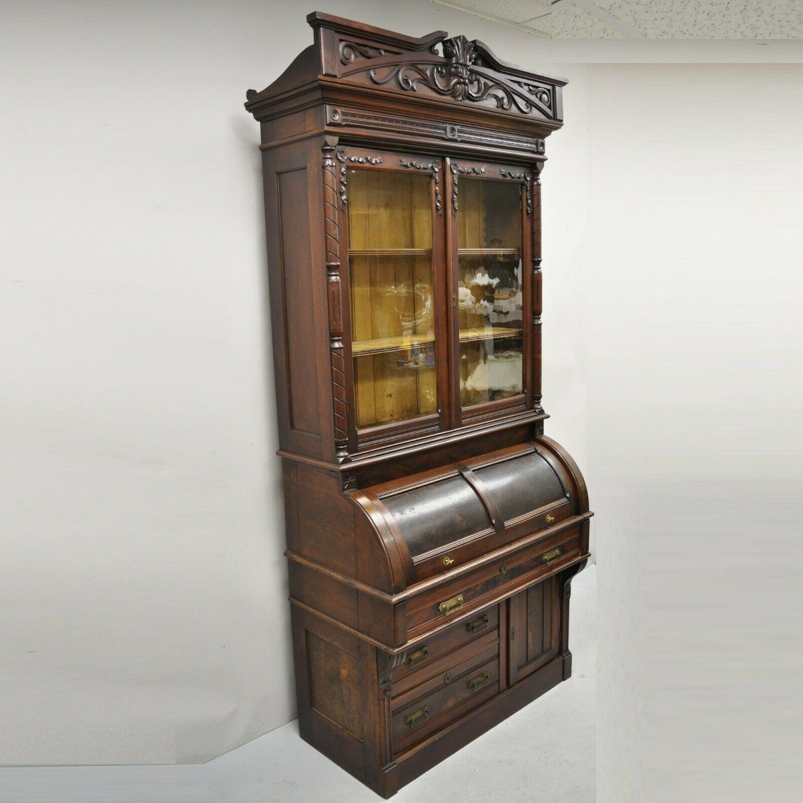 Antique Victorian Burl walnut cylinder roll secretary desk bookcase cabinet. Item features a carved north wind face pediment, original wavy glass, pull out writing surface, beautiful wood grain, nicely carved details, 3 part construction, working
