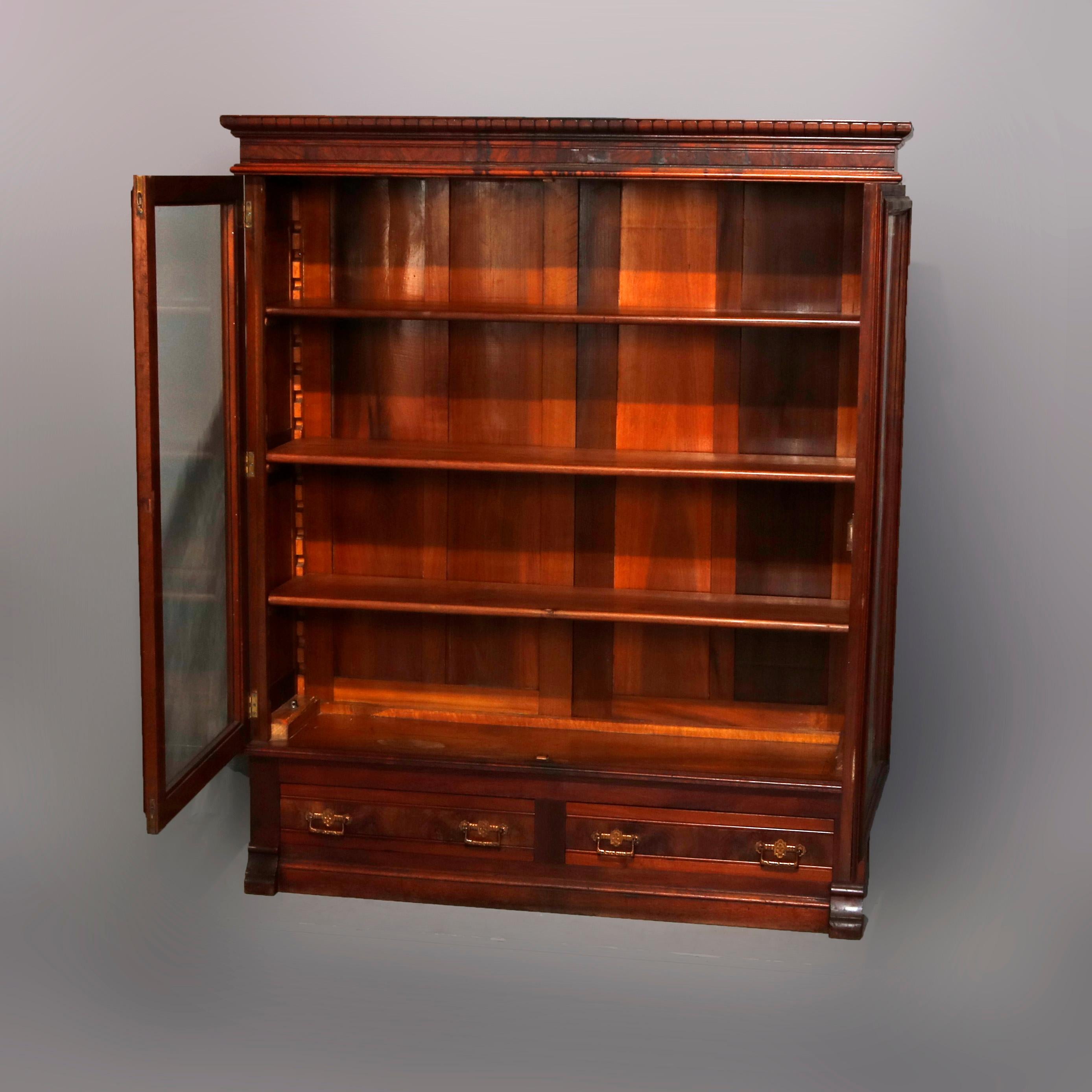 An antique Victorian enclosed bookcase offers burl paneled construction with upper case having double glass doors opening to interior with adjustable shelving and surmounting base with two drawers, circa 1890

Measures: 60