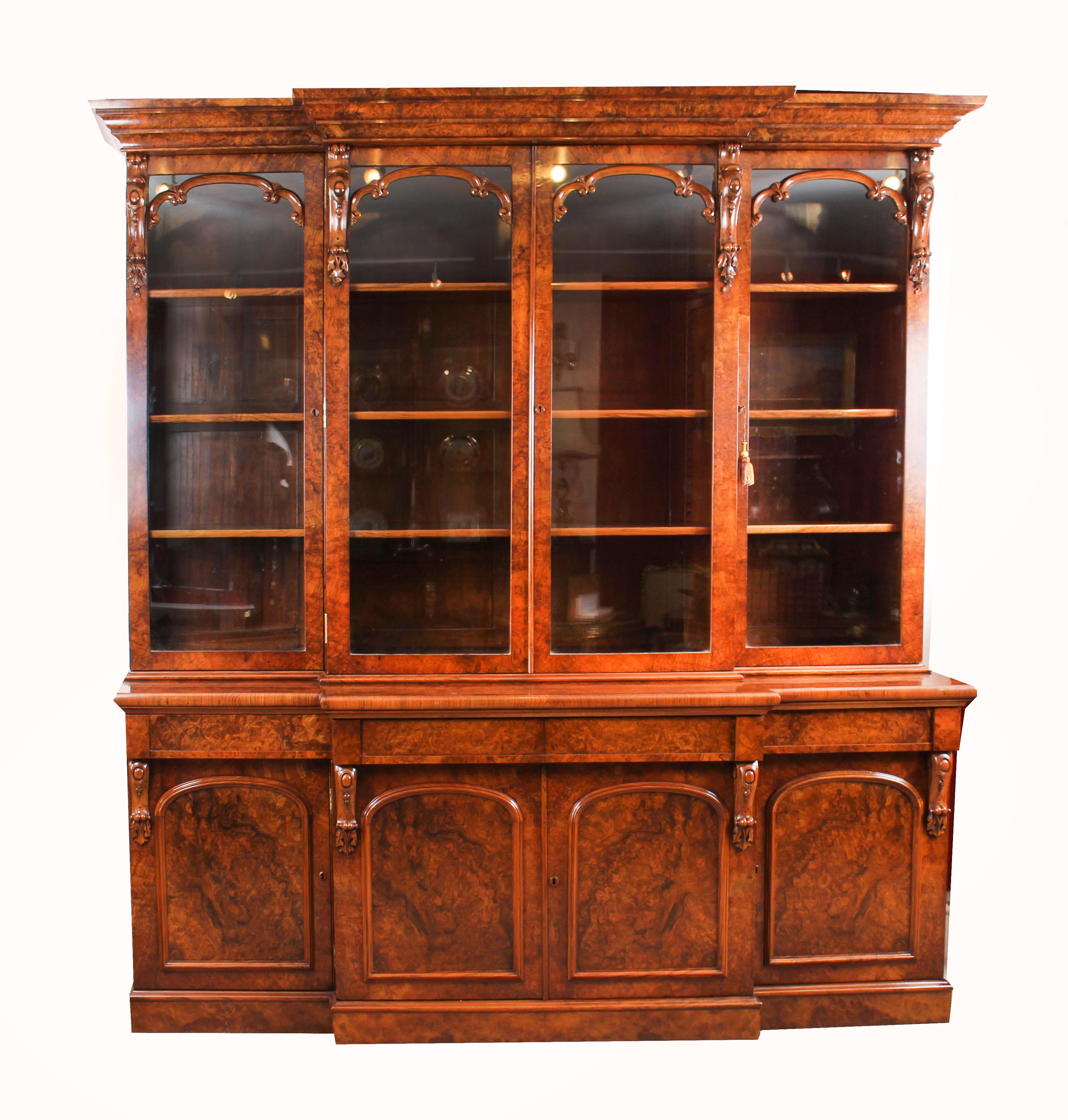 A stunning antique English early Victorian top quality four door breakfront bookcase, masterfully crafted in rich burr walnut, circa 1850 in date.

This magnificent bookcase features a flared breakfront cornice over four glazed doors with decorative