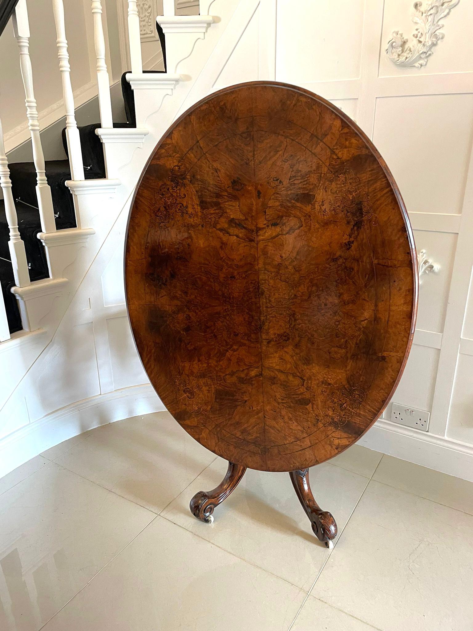 Antique Victorian burr walnut inlaid centre table having a burr walnut inlaid oval top with a thumb moulded edge supported by a turned shaped carved column standing on four shaped carved cabriole legs with scroll feet and  original porcelain castors