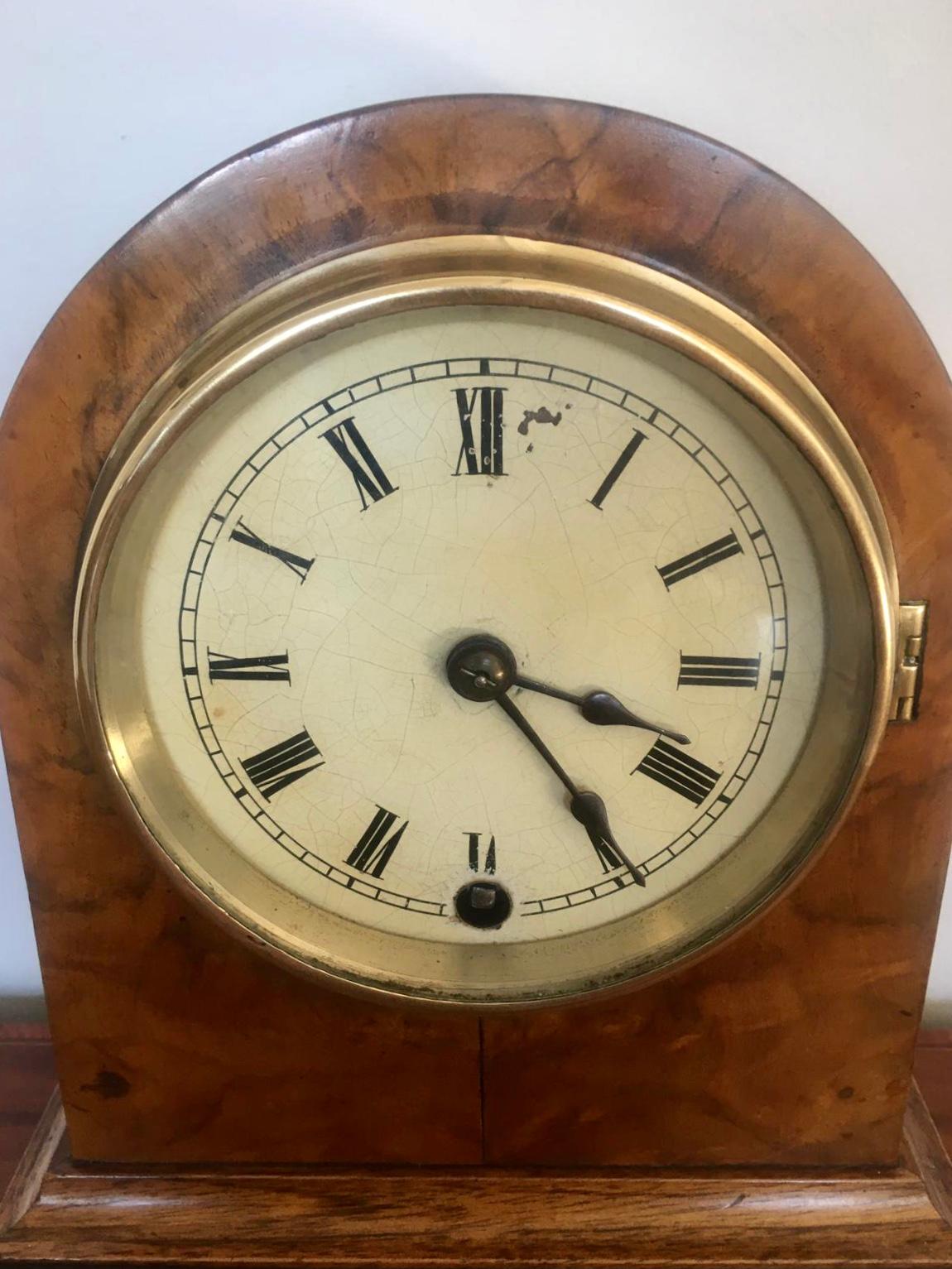 Antique Victorian burr walnut mantel clock having an arched top and burr walnut case standing on original walnut feet. It features a painted circular dial with original hands, brass bezel and opening back door to reveal the timepiece movement with
