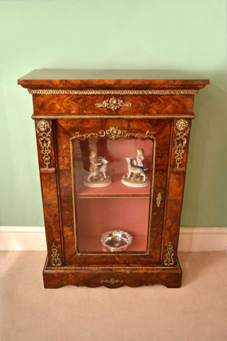 This is a beautiful antique Victorian pier cabinet, circa 1870 in date.

It has been accomplished in burr walnut with a glazed door, the whole beautifully inlaid. 

Adding to its truly unique character it is decorated with exquisite gilded