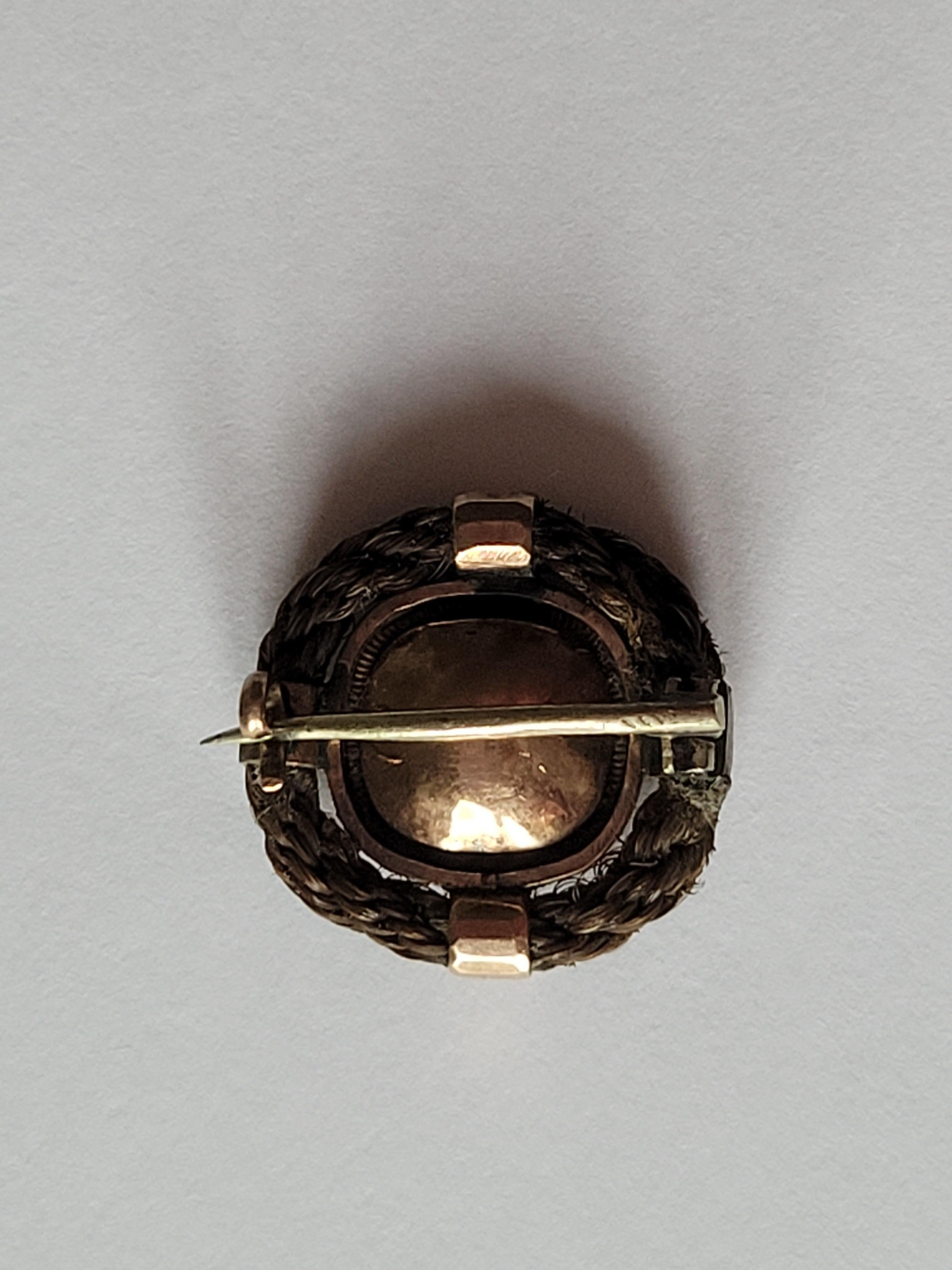 An Antique Victorian c.1840-1860s Mourning brooch. The stone in closed back rose gold setting surround by woven hair. Scottish origin.
Width 18mm.
Unmarked, tested 9 Carat Gold.
The brooch in very good condition for the age, a great collector's
