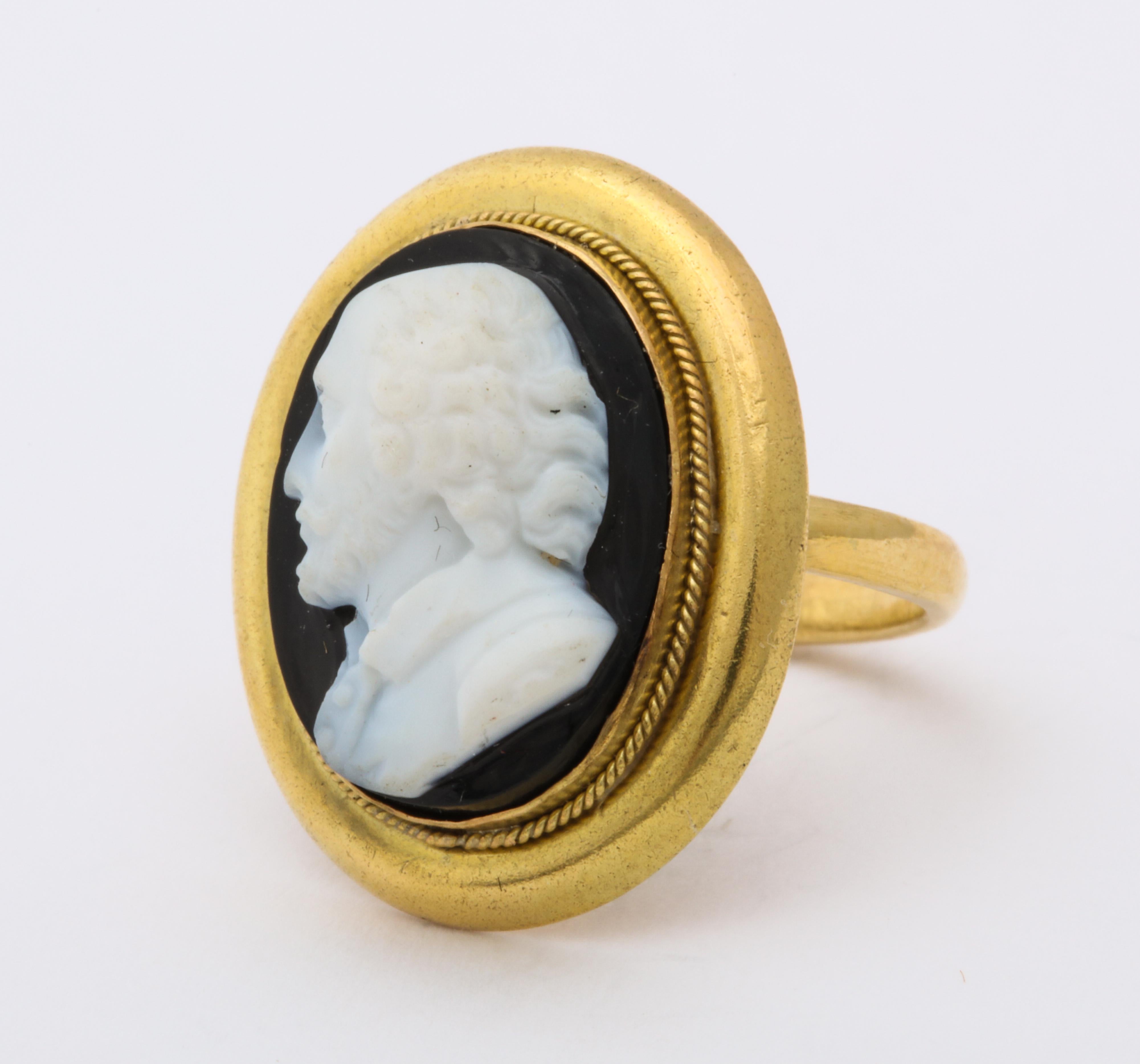 In a gentle oval of 18 kt gold rests a miniature profile of William Shakespeare wearing a buttoned shirt all carved in durable hard stone.  Imagine a black stone, banded with white, turned into a portrait by an artist who seeks enough white so that