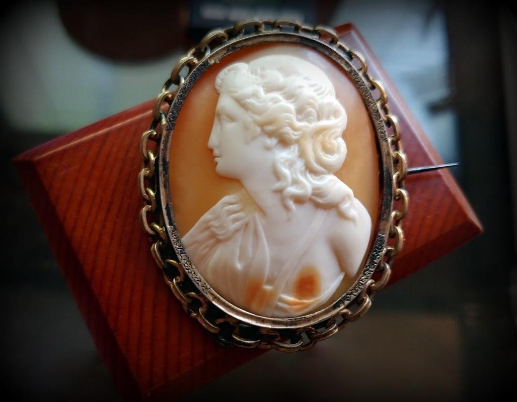 We are thrilled to present this amazing Victorian Cameo Brooch, dating back to the 1830s-1850s. The beautiful portrait of a young Greek lady is expertly carved into the shell with exceptional detail and relief.

The frame is made of pinchbeck, an