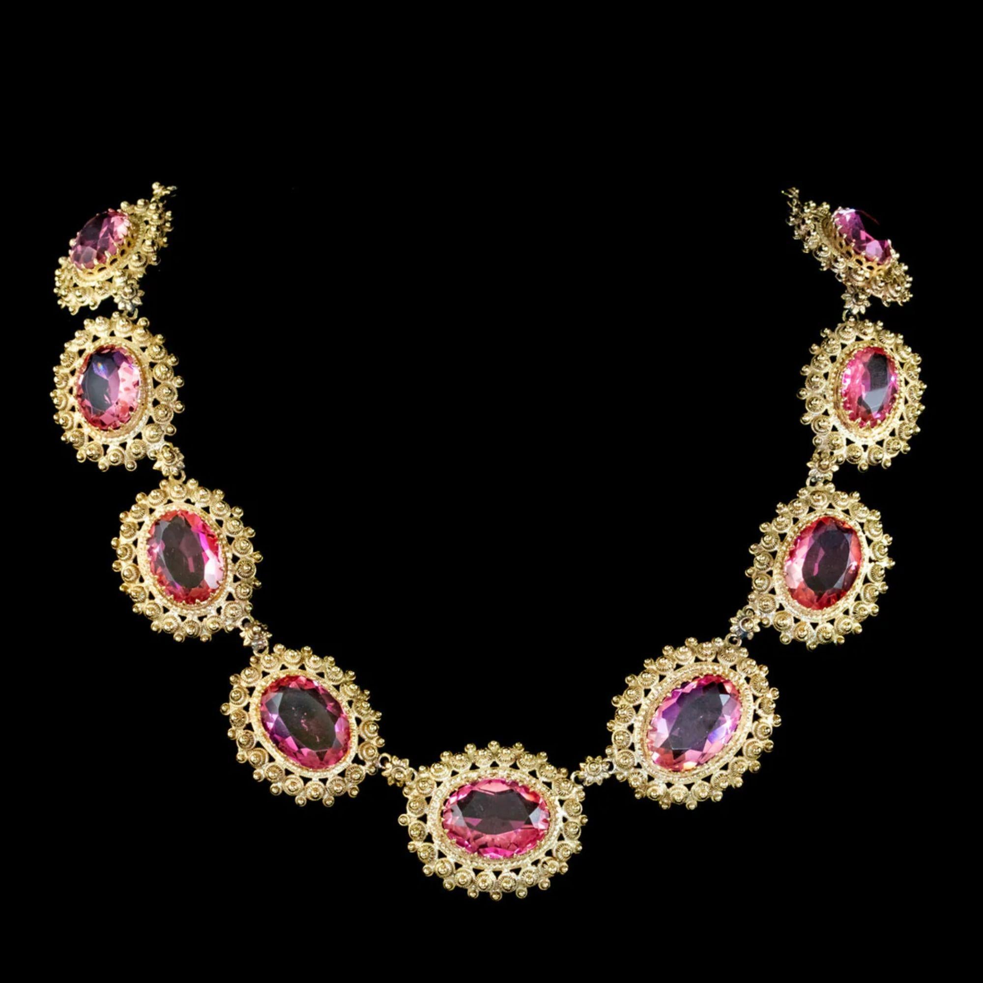 A grand Antique mid Victorian collar dating from Circa 1860. The piece is made up of large Pinchbeck links gilded in 18ct Yellow Gold with stunning Cannetille workmanship and flower shaped links in between.

A large pink Paste stone is also claw set