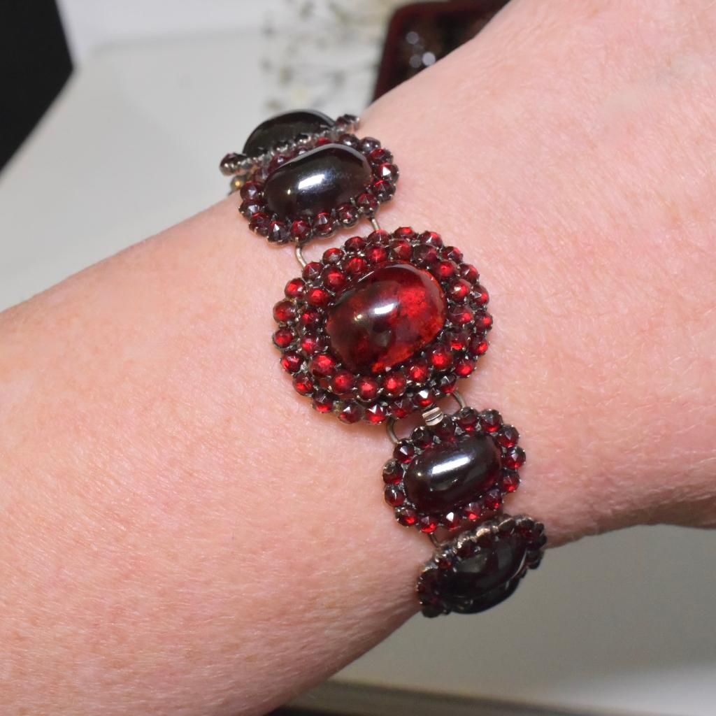 Featuring a total of eleven (11) cabochon garnets, the largest set to the push-in box clasp weighs approximately 7.2 carats - 1.4cm x 1.1cm - and is halo set in two tiered style with round- rose-cut Bohemian garnets. 

A further ten (10) panels are