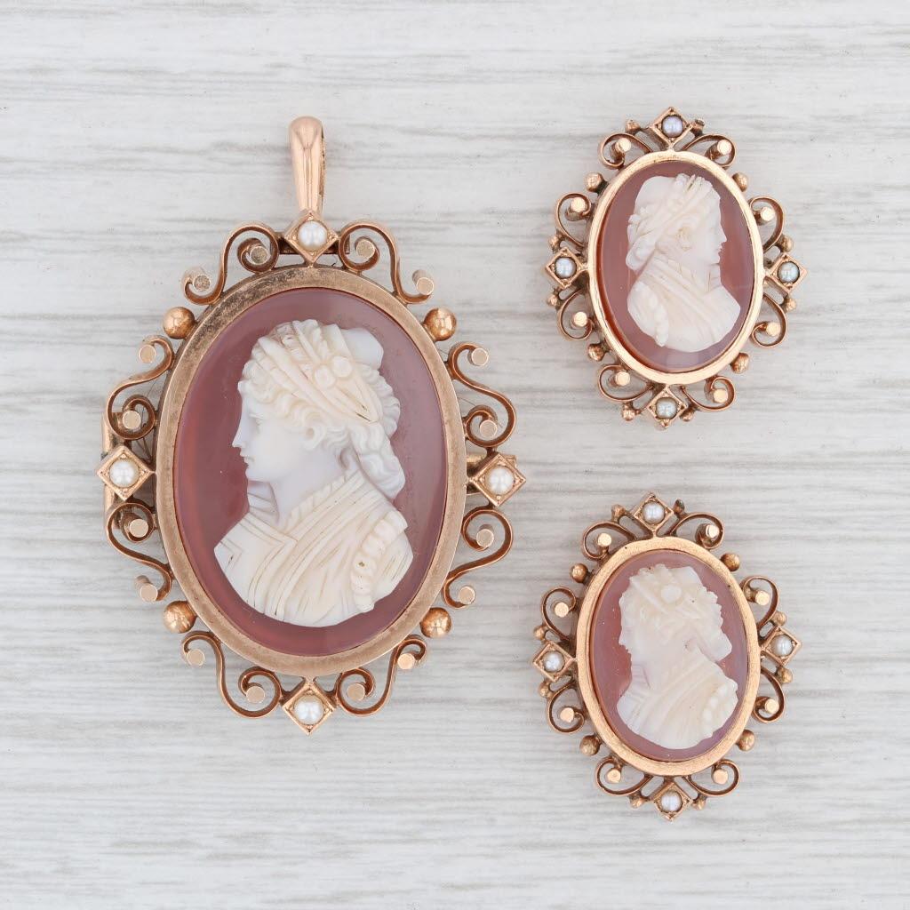 This beautiful antique Victorian set features a larger cameo brooch (which can also be worn as a pendant by a hinged folding bail) and two matching smaller cameo pins. The back of the larger brooch has a locket design with a see through glass back
