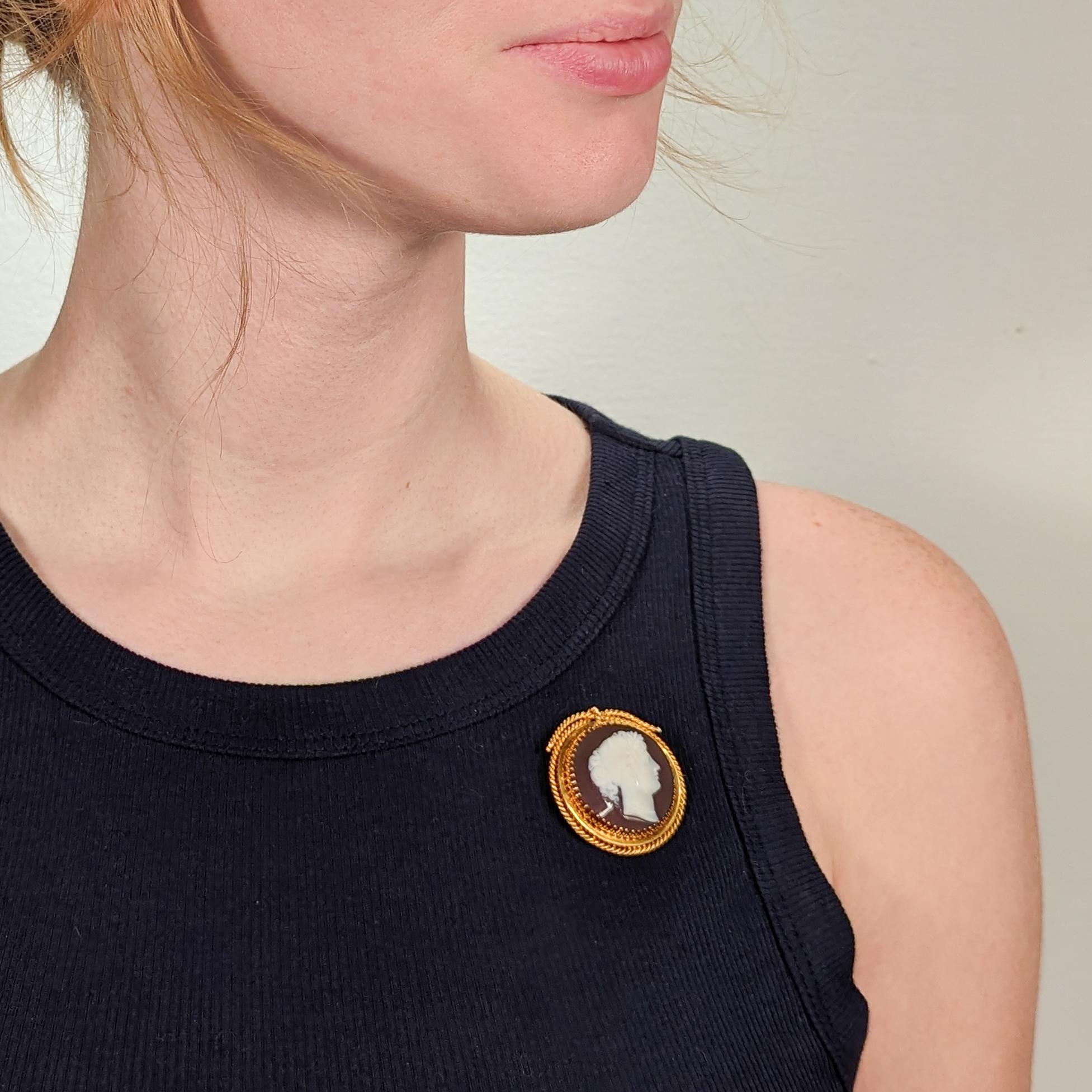 A fine antique cameo brooch.

In 18k gold.

With a cameo carved agate medallion of a beautiful young woman with headband, earrings, and pearl (or beaded) necklace.

Prong-set in a wide circular setting with applied rope cables around its