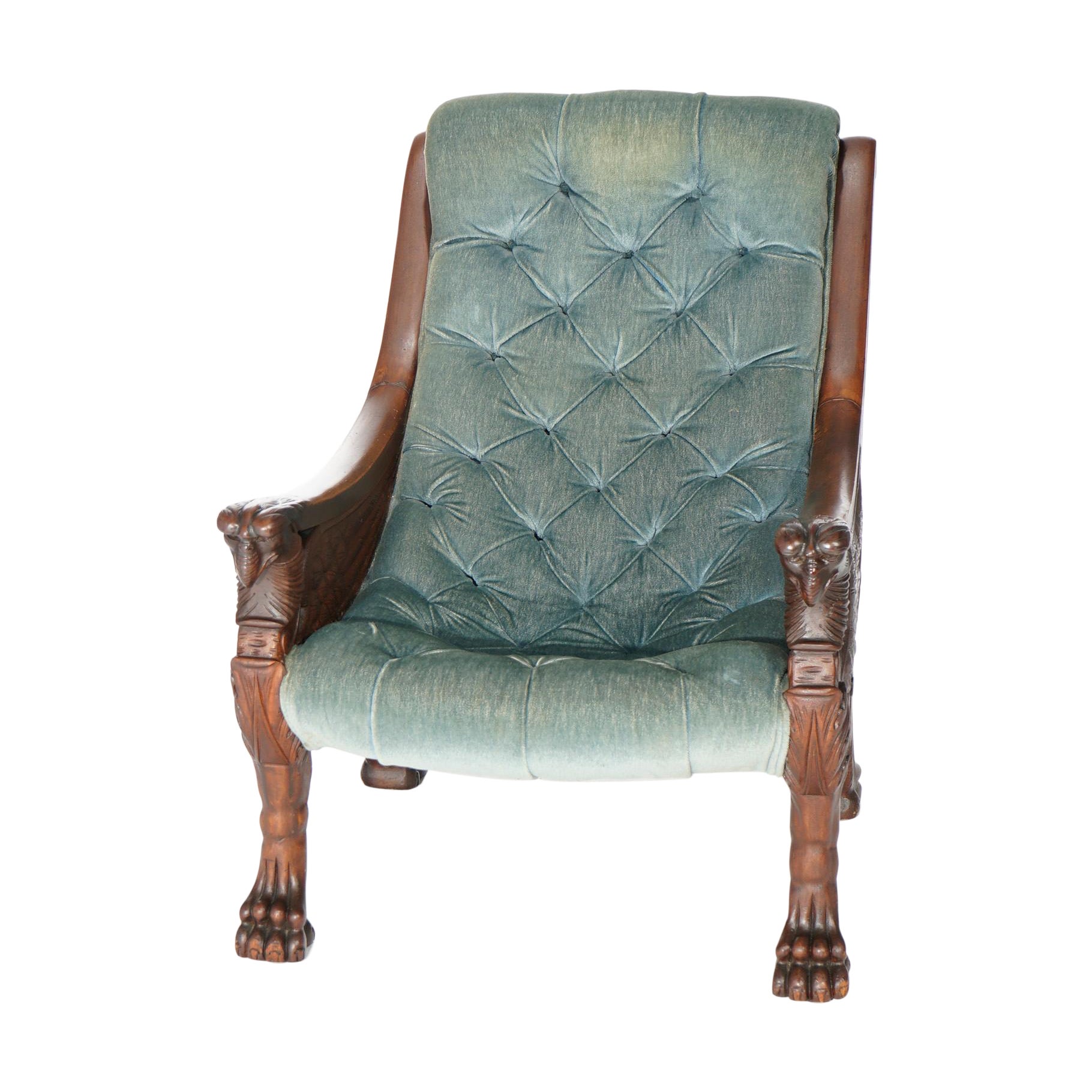An antique Victorian figural lolling chair offers button back upholstery on mahogany frame with carved griffin (eagle) arms and raised on legs with carved paw feet, c1900

Measures- 36.5'' H x 27.75'' W x 37'' D.